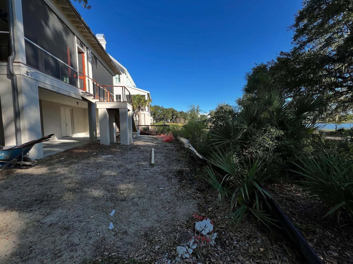 Unfinished apartment building beside a gravel path, with trees and blue sky on a sunny day