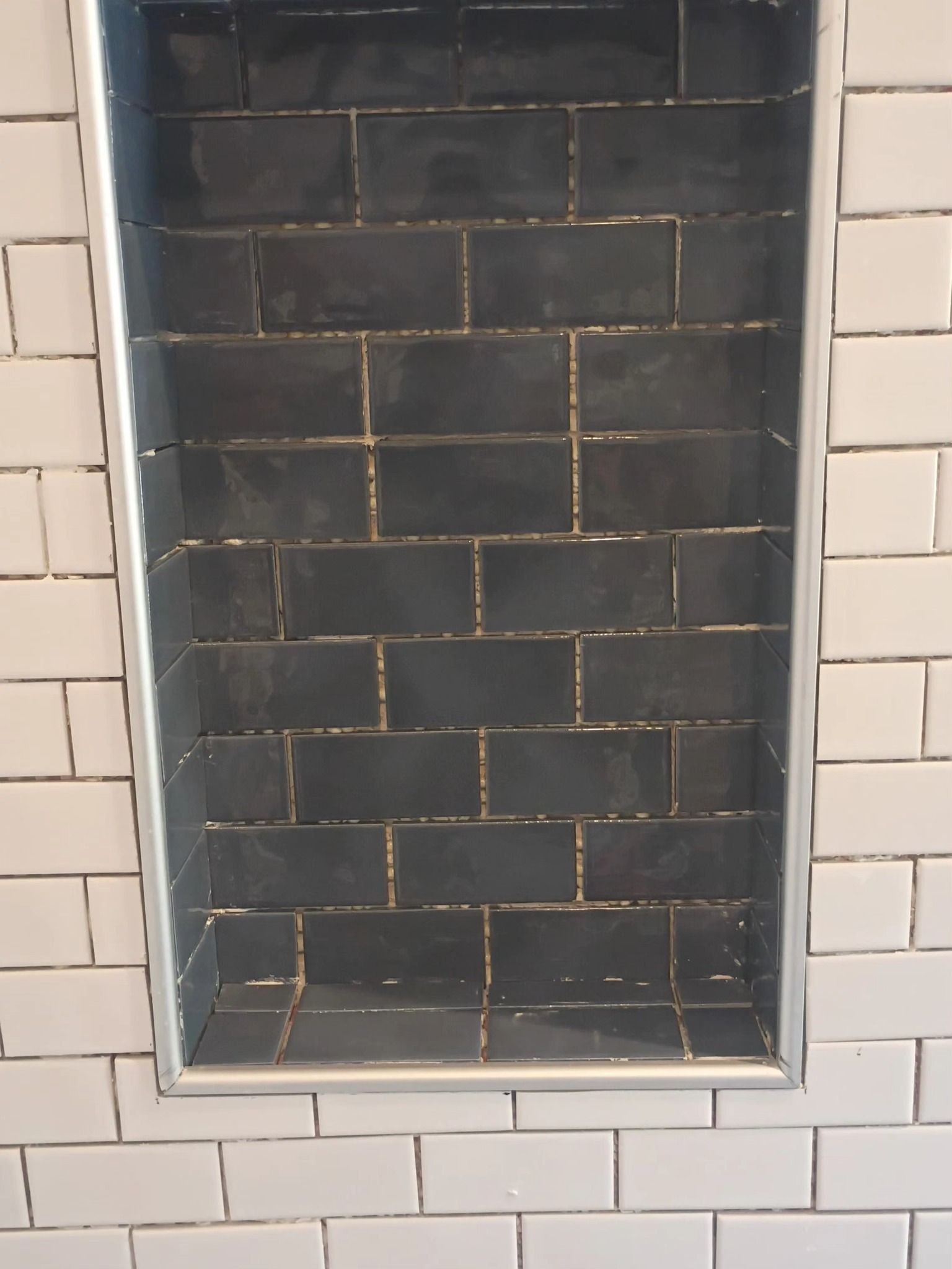 Recessed dark-tiled fireplace surrounded by white subway tiles
