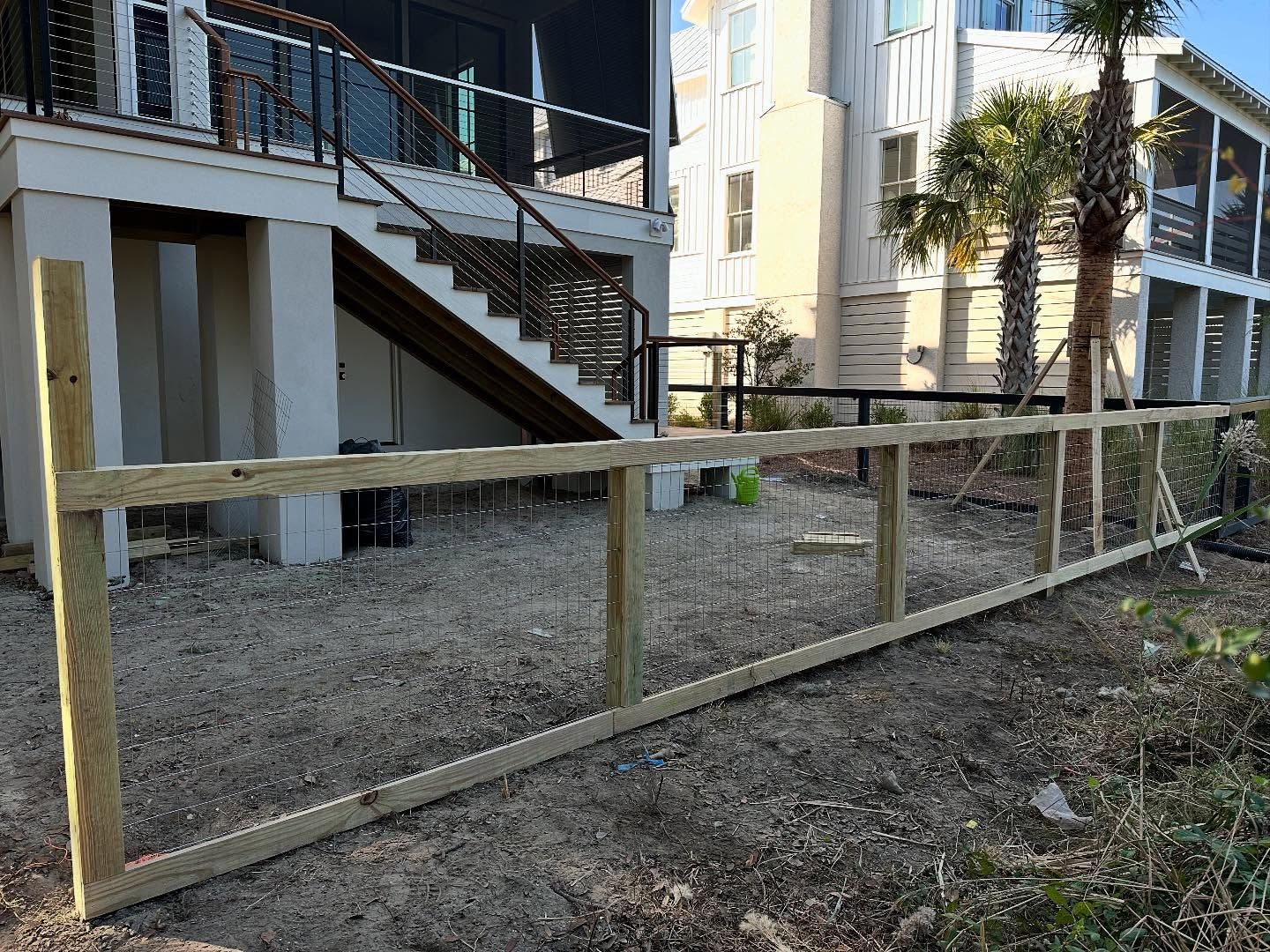 Wooden fence panels lining a dirt path beside apartment buildings and stairs