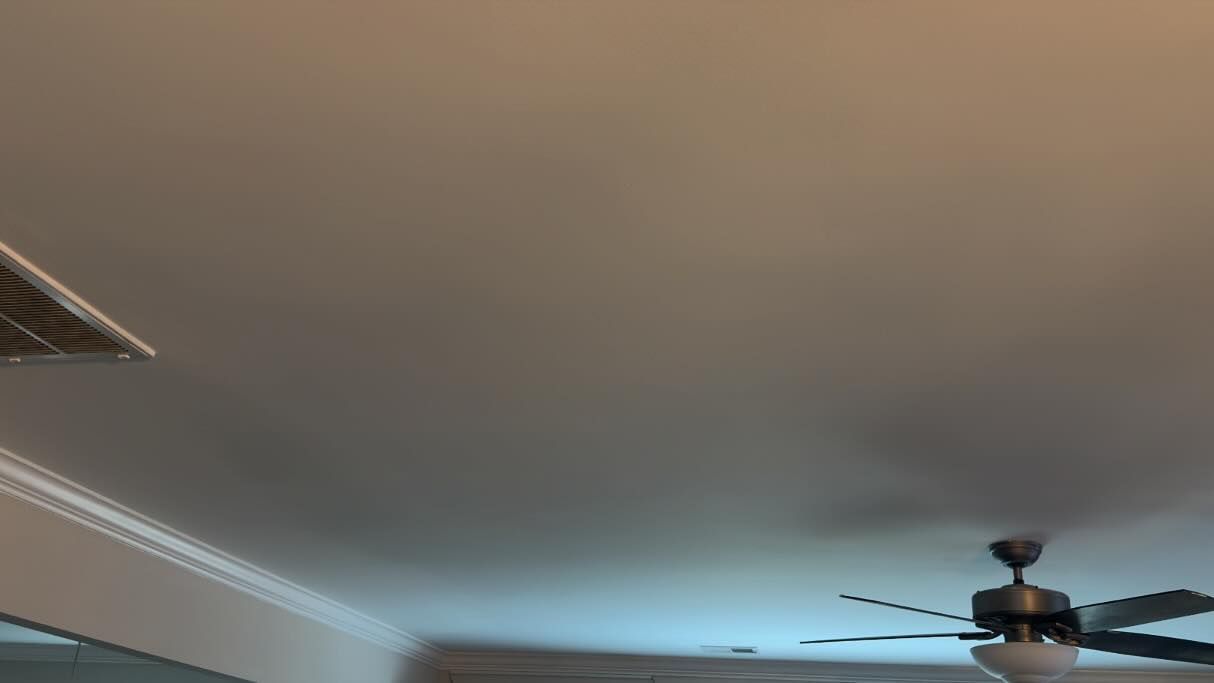 Ceiling with a vent, crown molding, and a ceiling fan in a softly lit room.