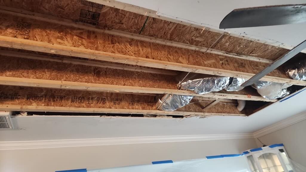 Exposed ceiling joists with insulation and ductwork above a room under construction