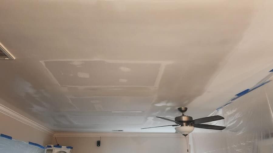 Ceiling with patchwork repairs and a ceiling fan in a room under renovation