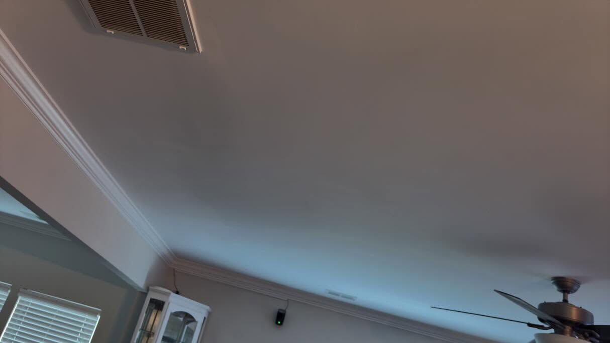 Ceiling with white crown molding, a vent, and a dark ceiling fan in a room with blinds.