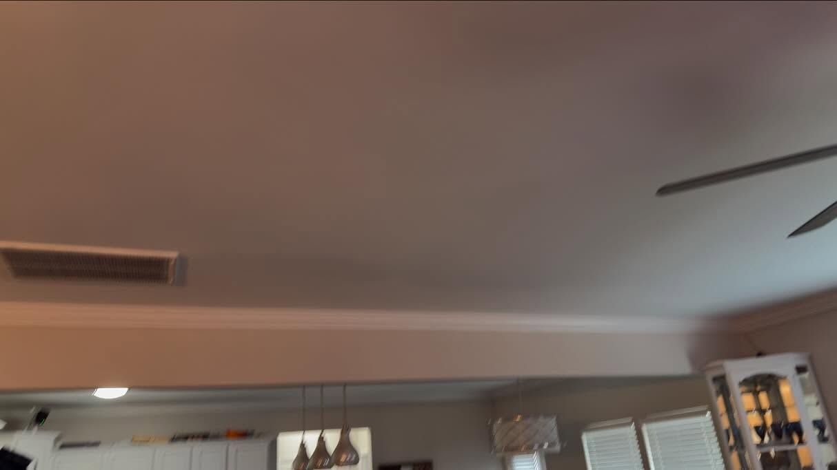 Living room ceiling with recessed lights, a vent, and a ceiling fan above cabinets and windows