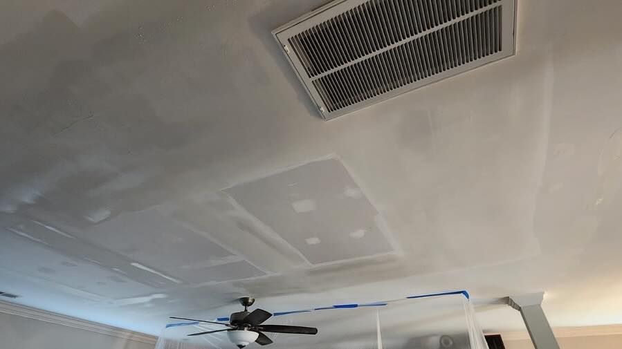 Ceiling with patchwork drywall, air vent, and ceiling fan in a room under repair