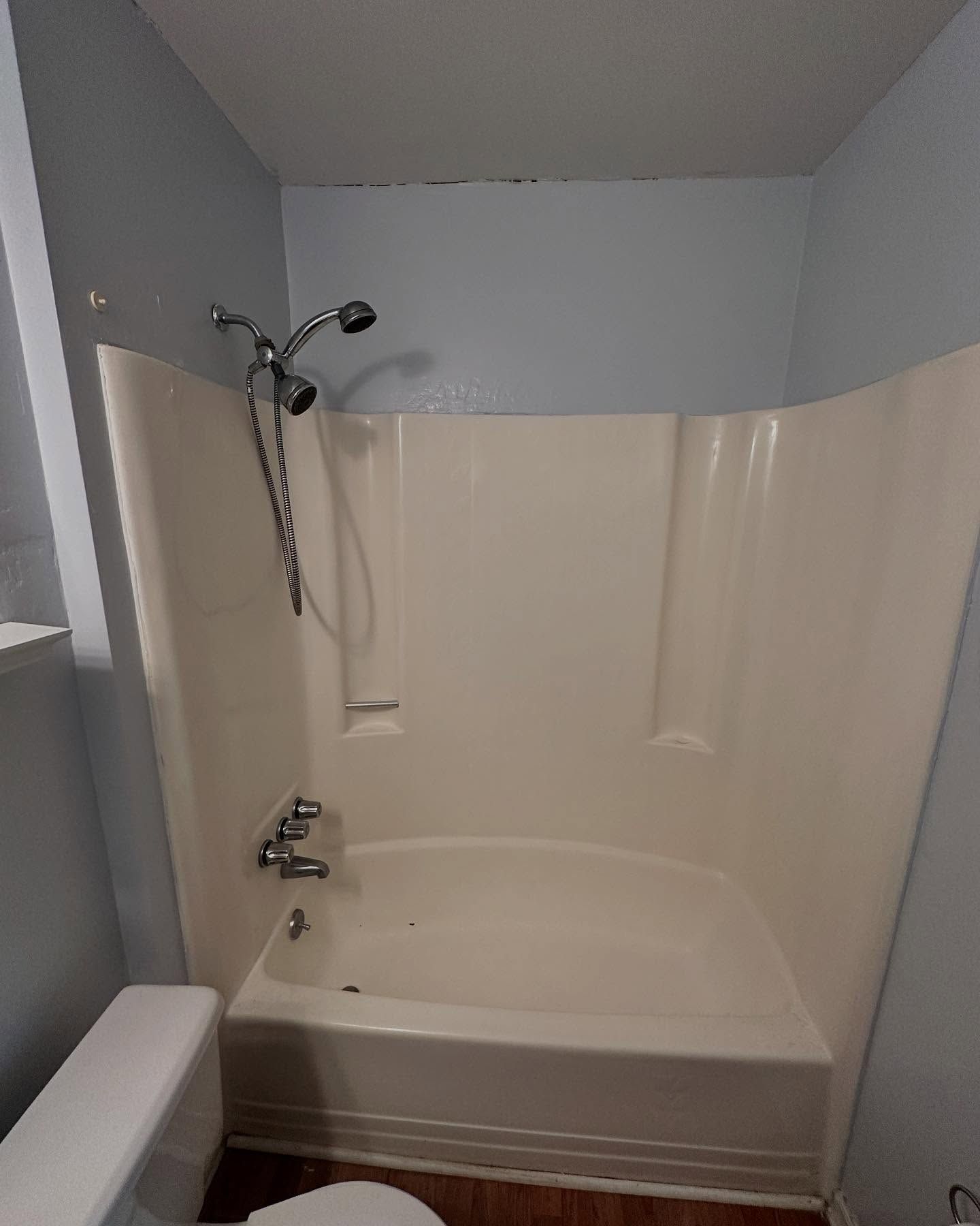 Empty white bathtub with shower curtain rod and gray bathroom walls