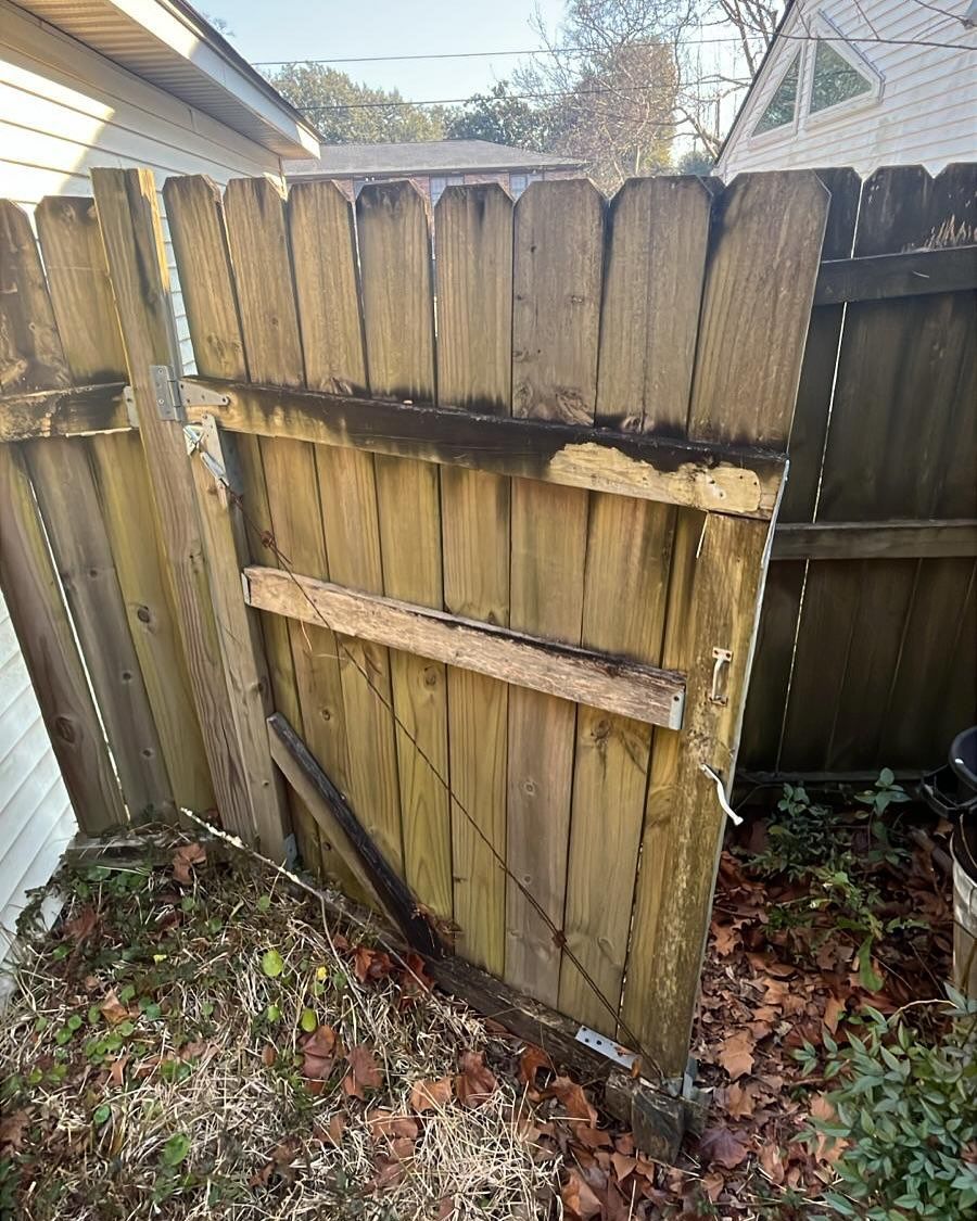 Broken weathered wooden fence gate leaning in a yard with fallen leaves
