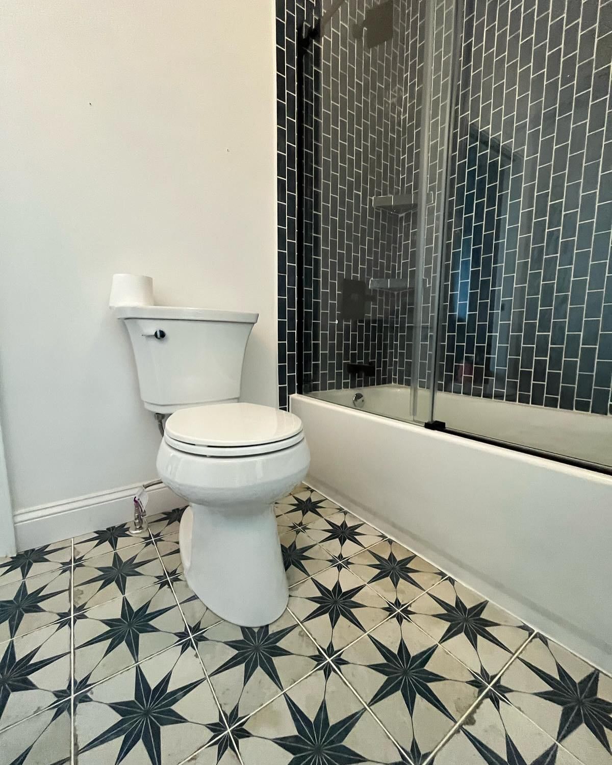 Bathroom with white toilet, patterned tile floor, and shower curtain on the right