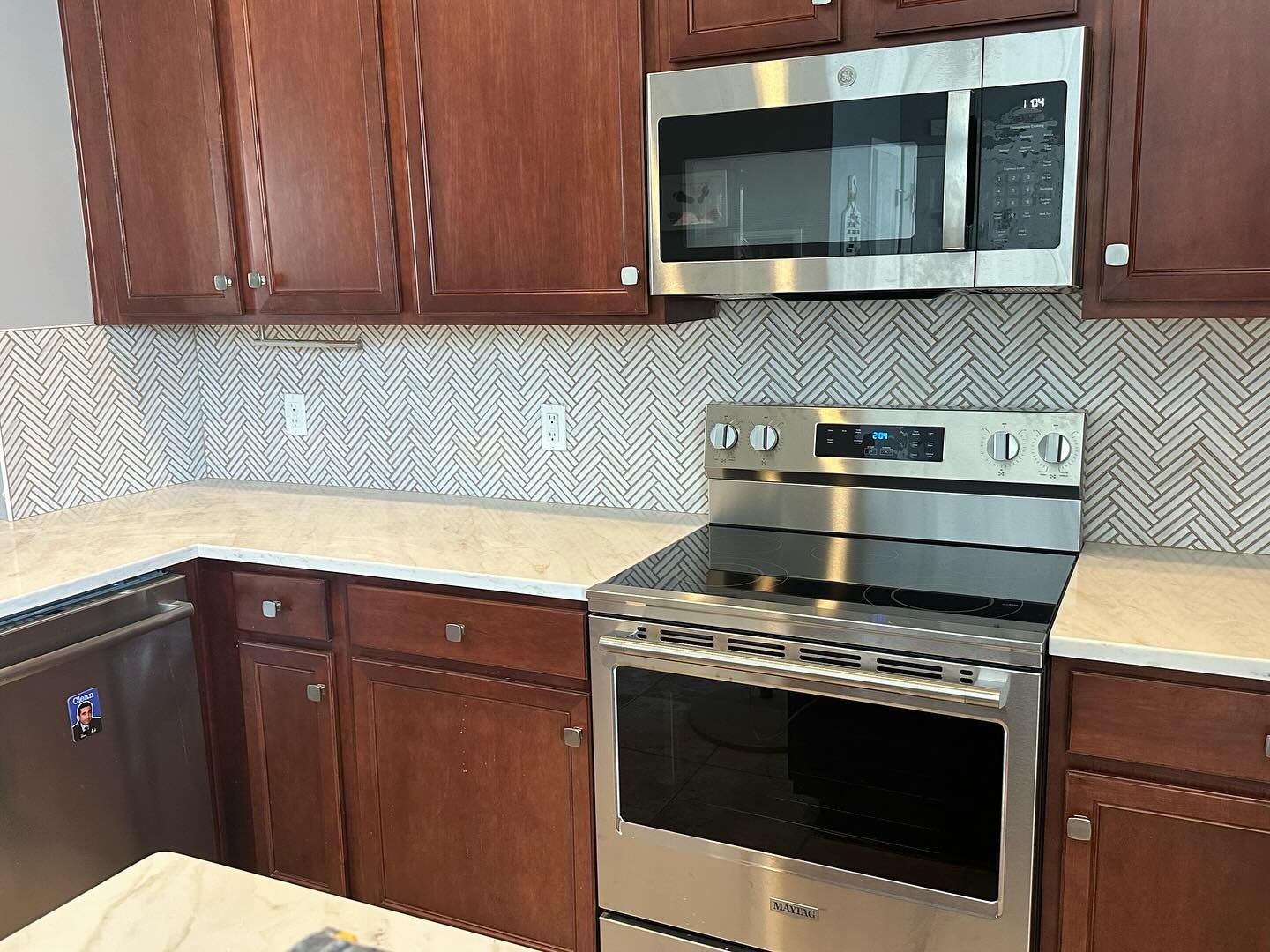 Modern kitchen with brown cabinets, stainless steel stove and microwave, and light countertops