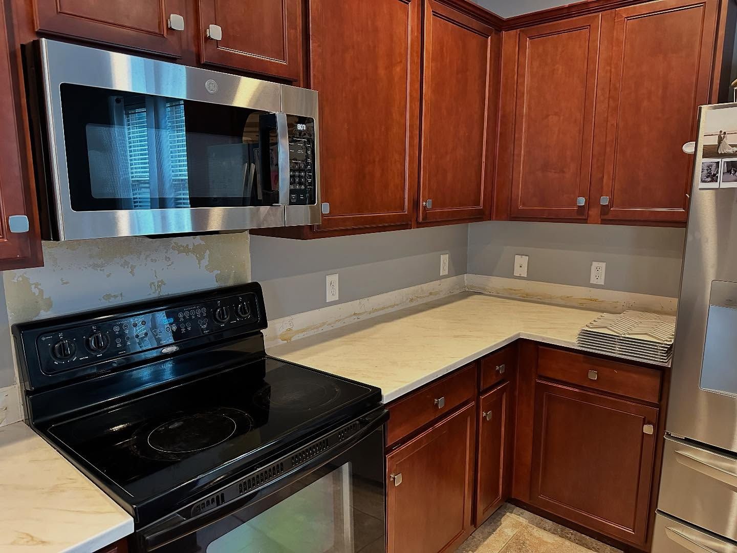 Modern kitchen with dark wood cabinets, stainless steel appliances, and light countertops