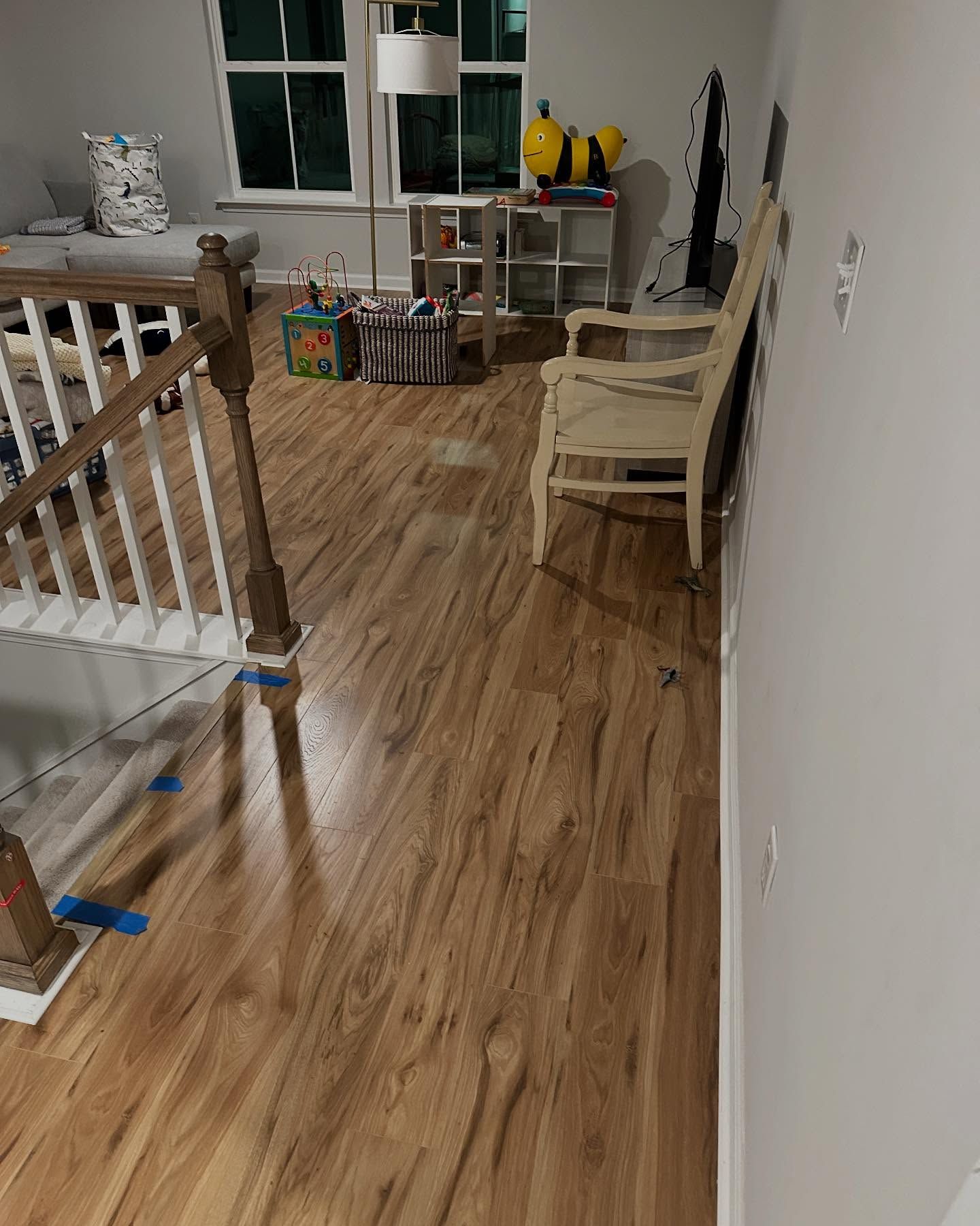 Indoor hallway with wood floors, staircase railings, and a small seating area by the window