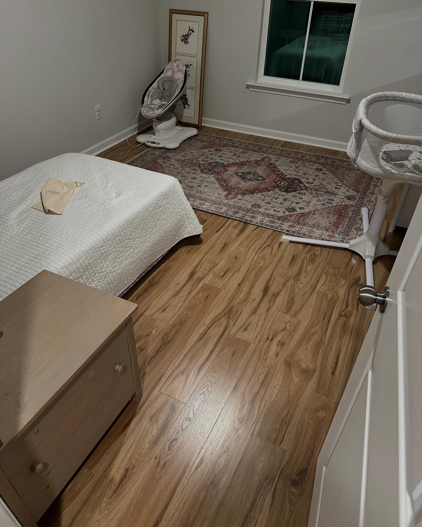 Small bedroom with a bed, dresser, rug, fan, window, and chair on wood flooring.