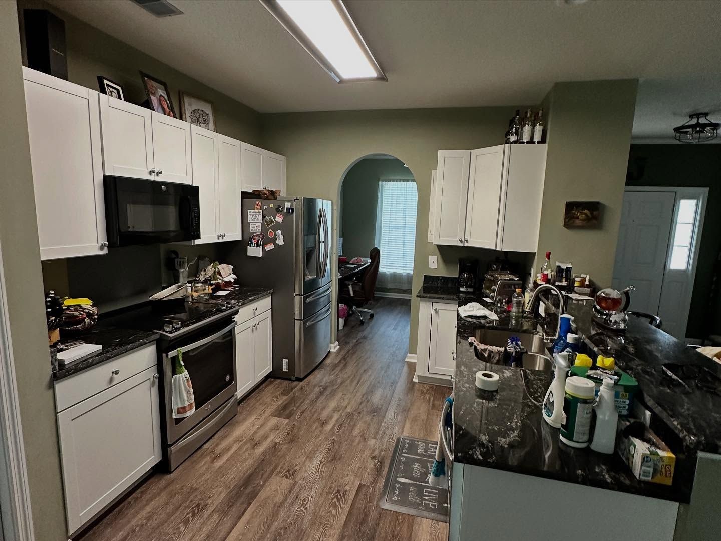 Modern kitchen with white cabinets, black appliances, and a cluttered island countertop