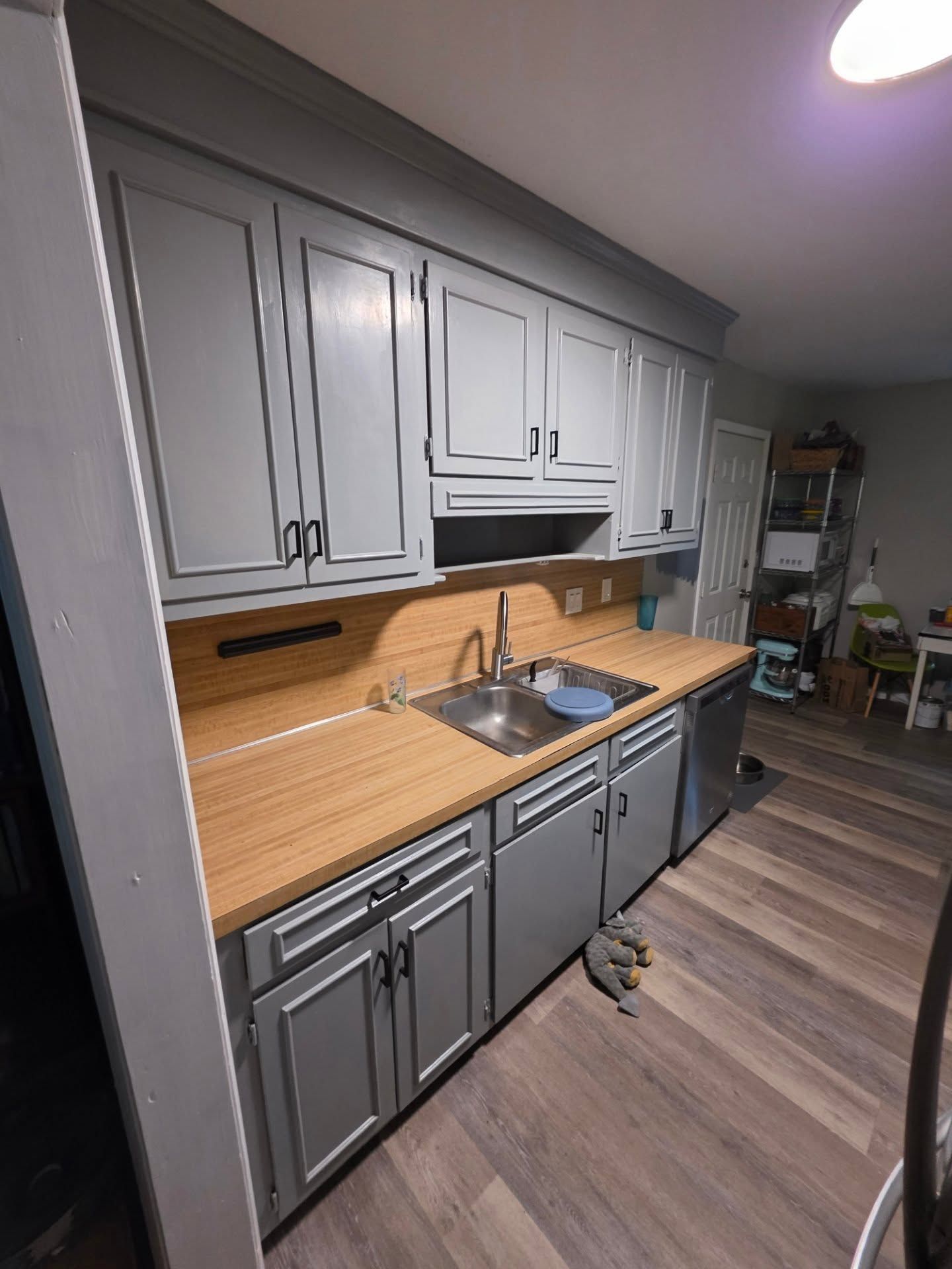 Kitchen with gray cabinets, wood countertops, and stainless sink in a modern home interior.