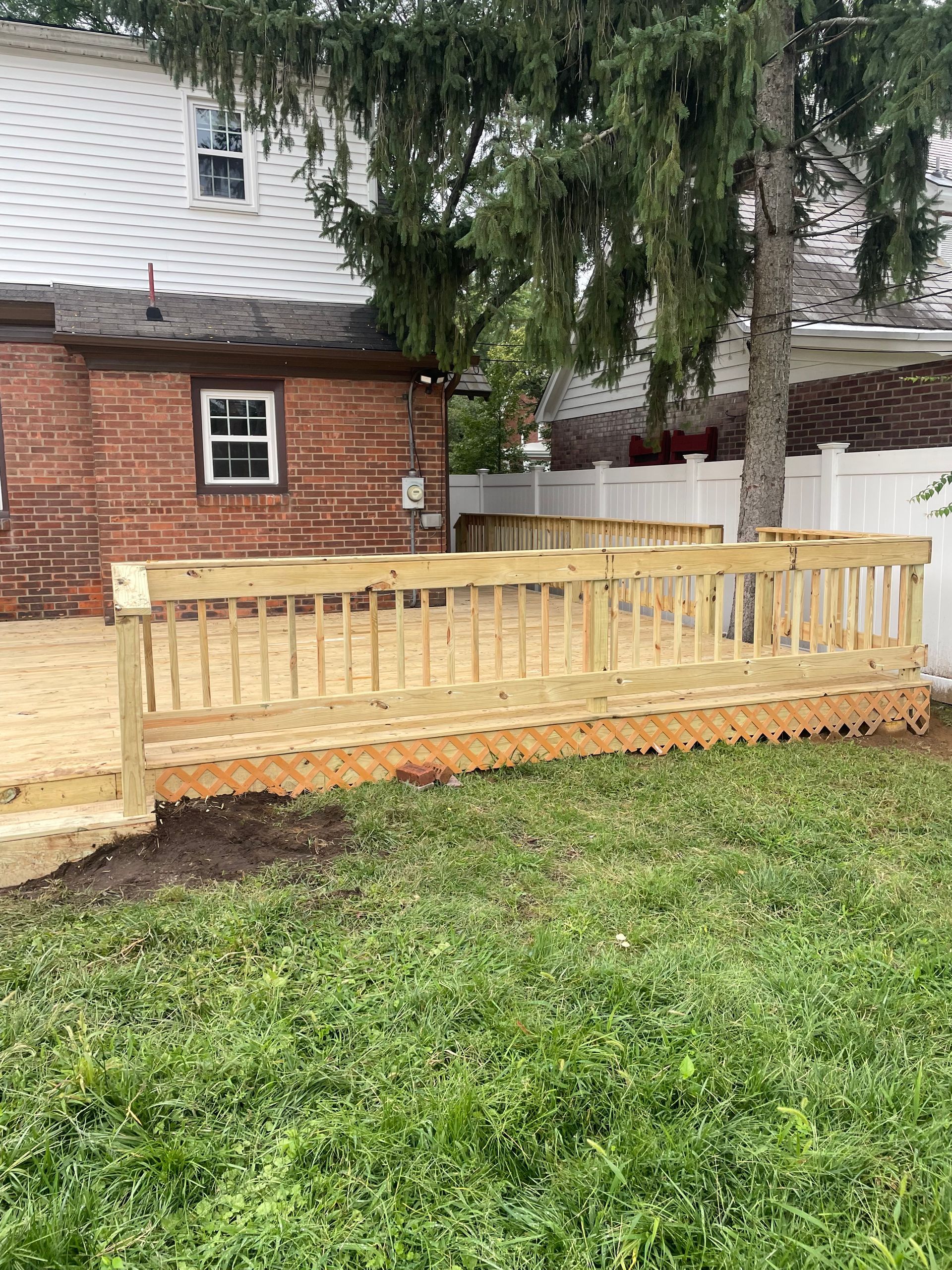 A wooden deck is in the backyard of a house.