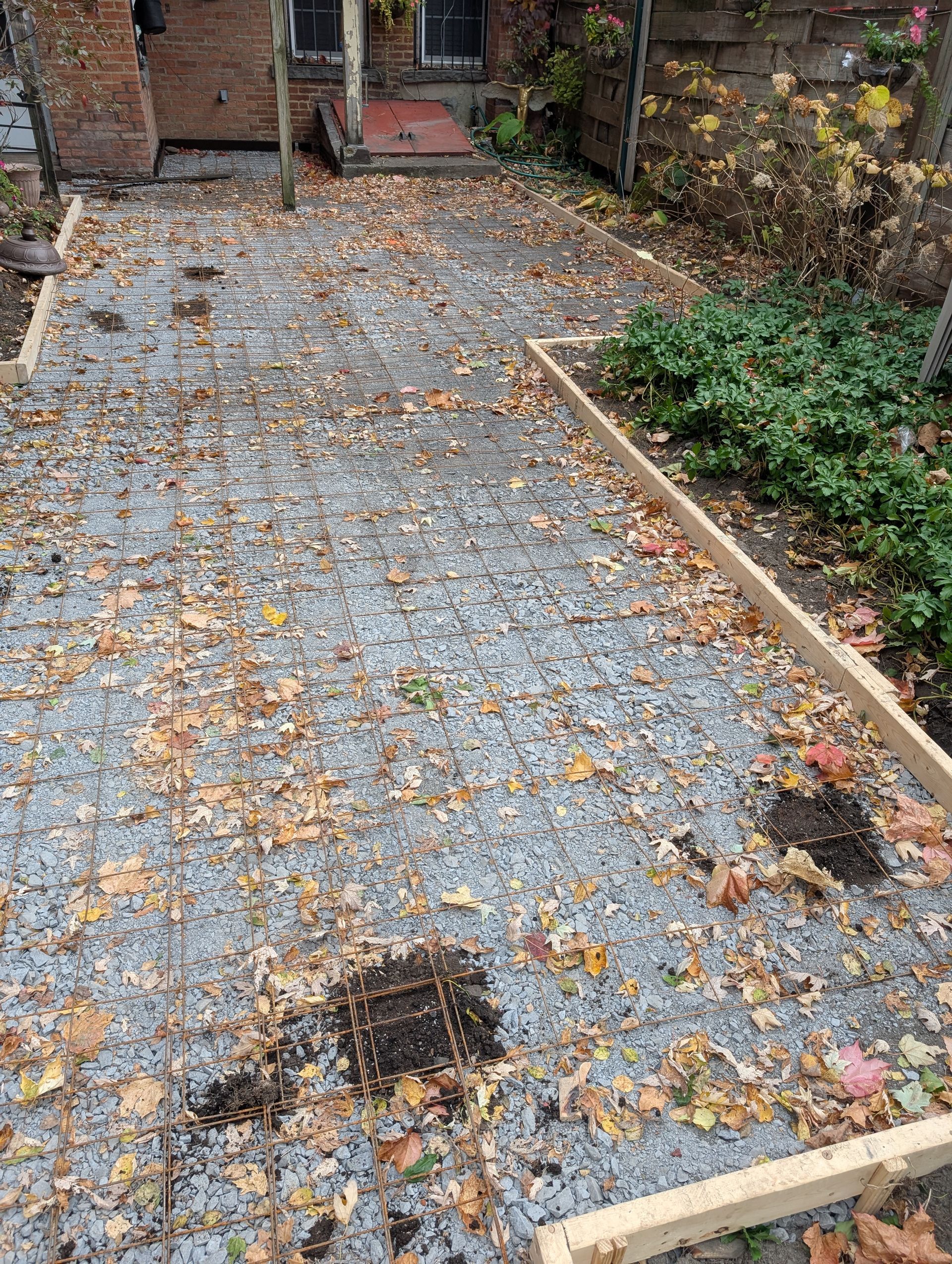 A gravel driveway with leaves on the ground in front of a house.