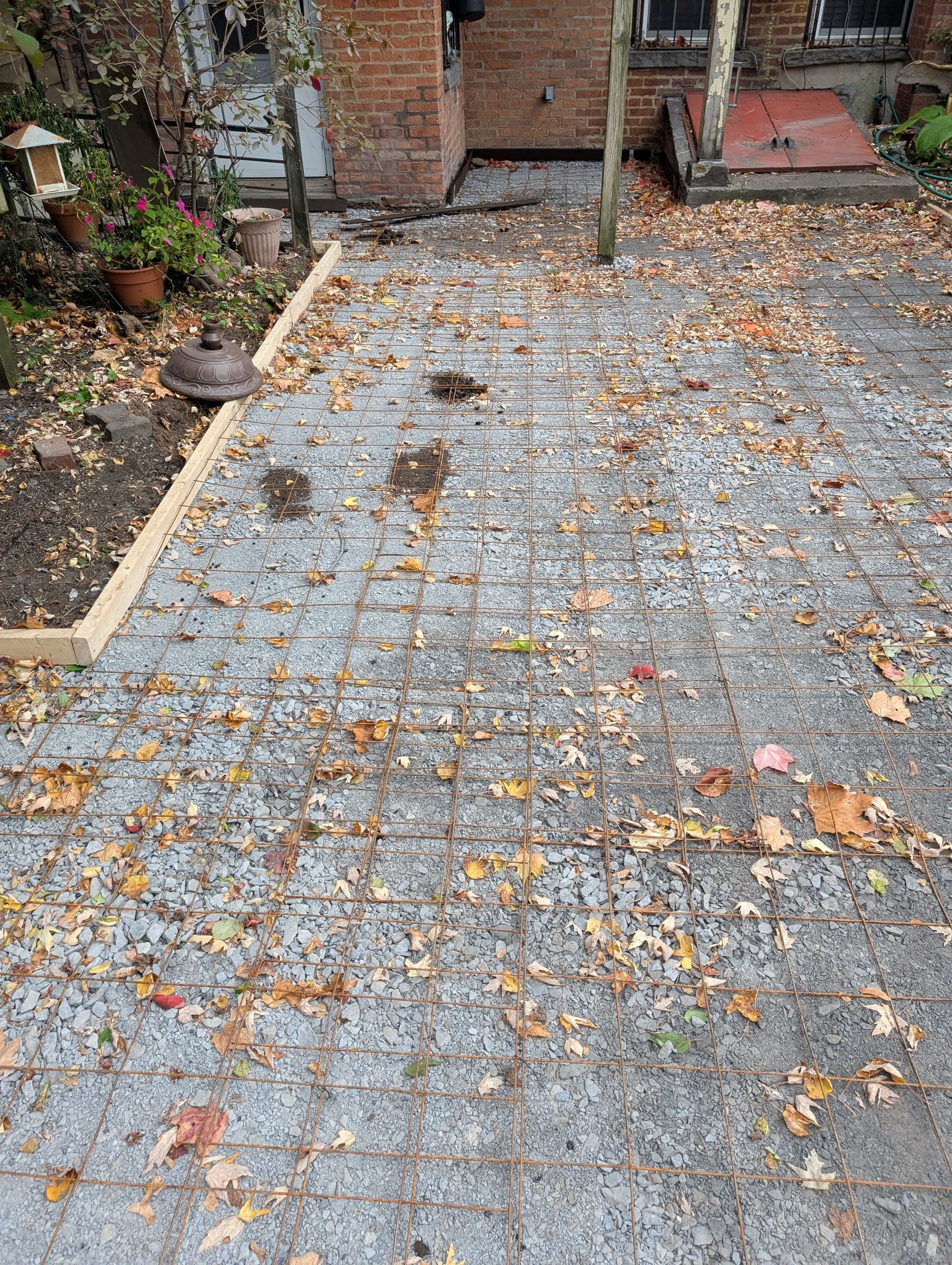 A brick driveway with leaves on it and a brick building in the background.