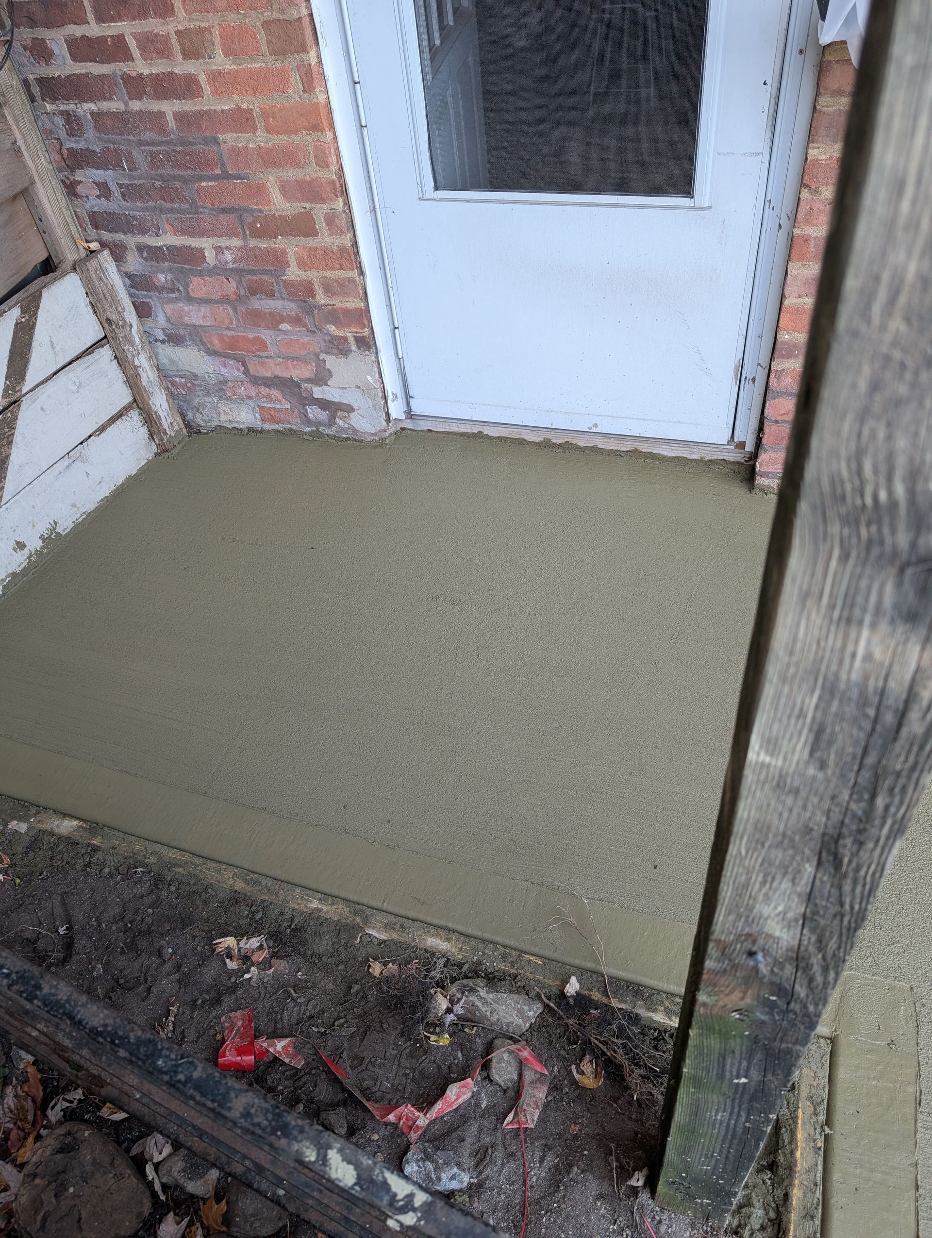 A concrete walkway is being built in front of a brick building.