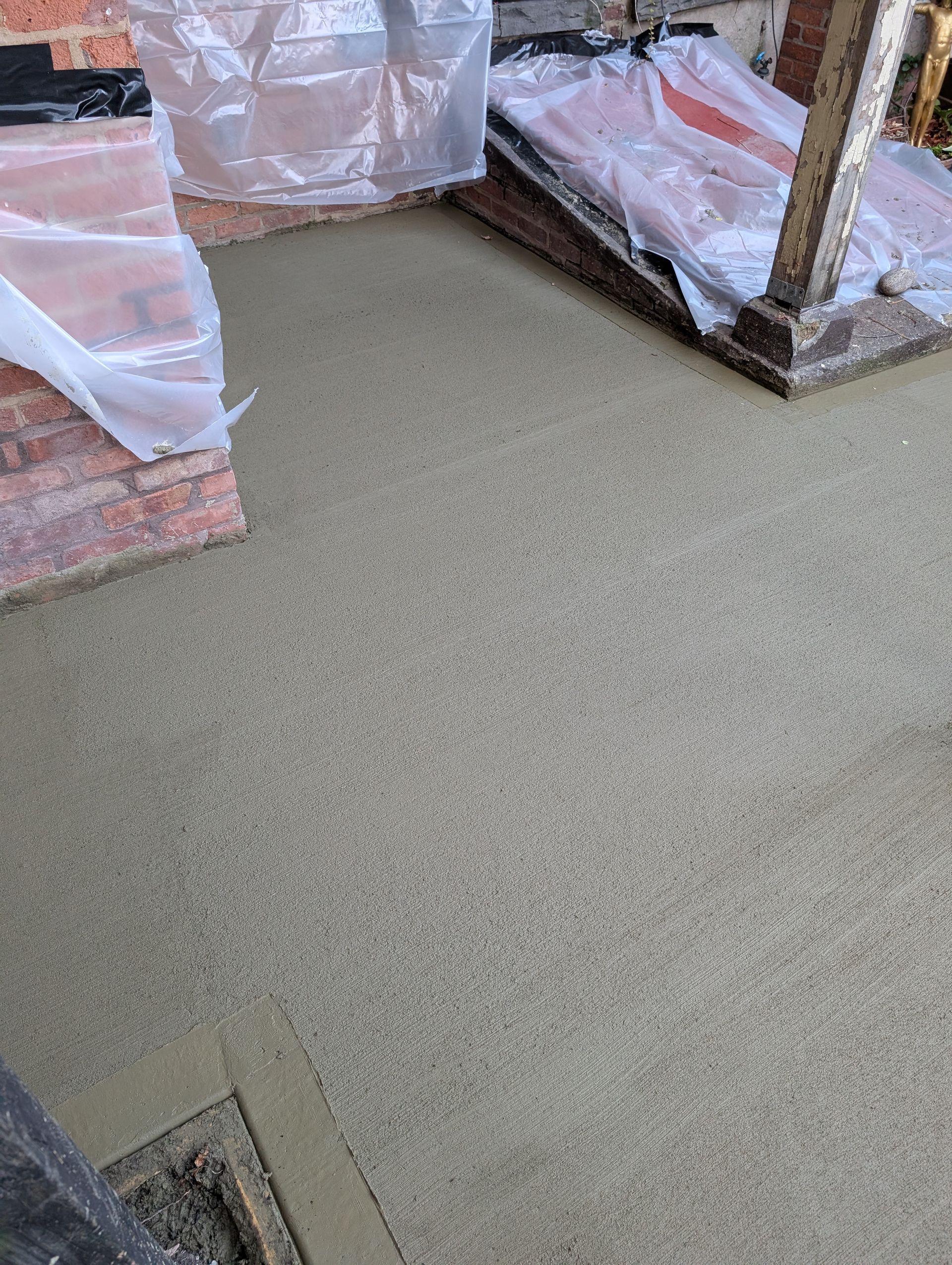 A concrete floor with a brick wall in the background.