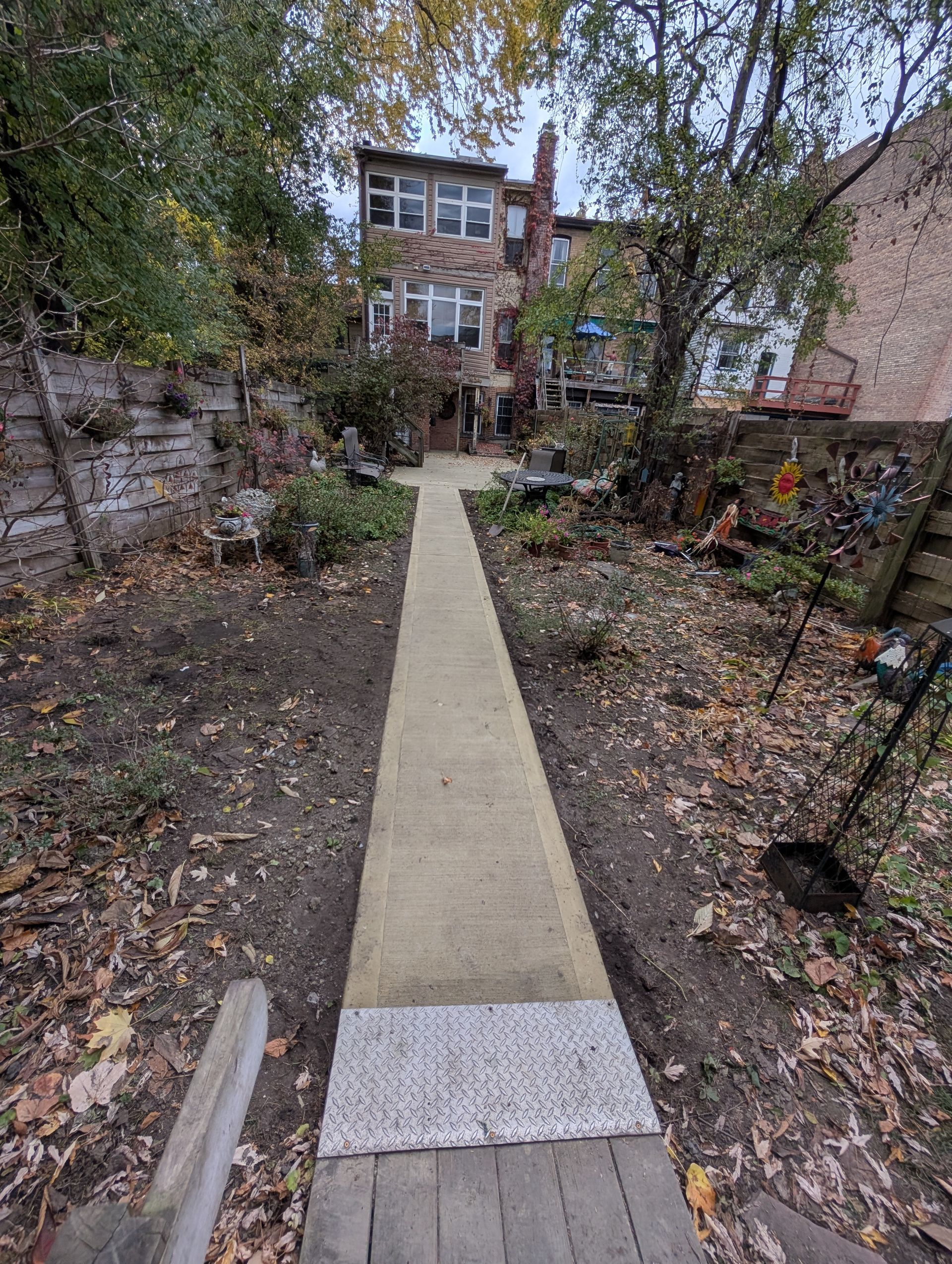 A wooden walkway leading to a house in a backyard.