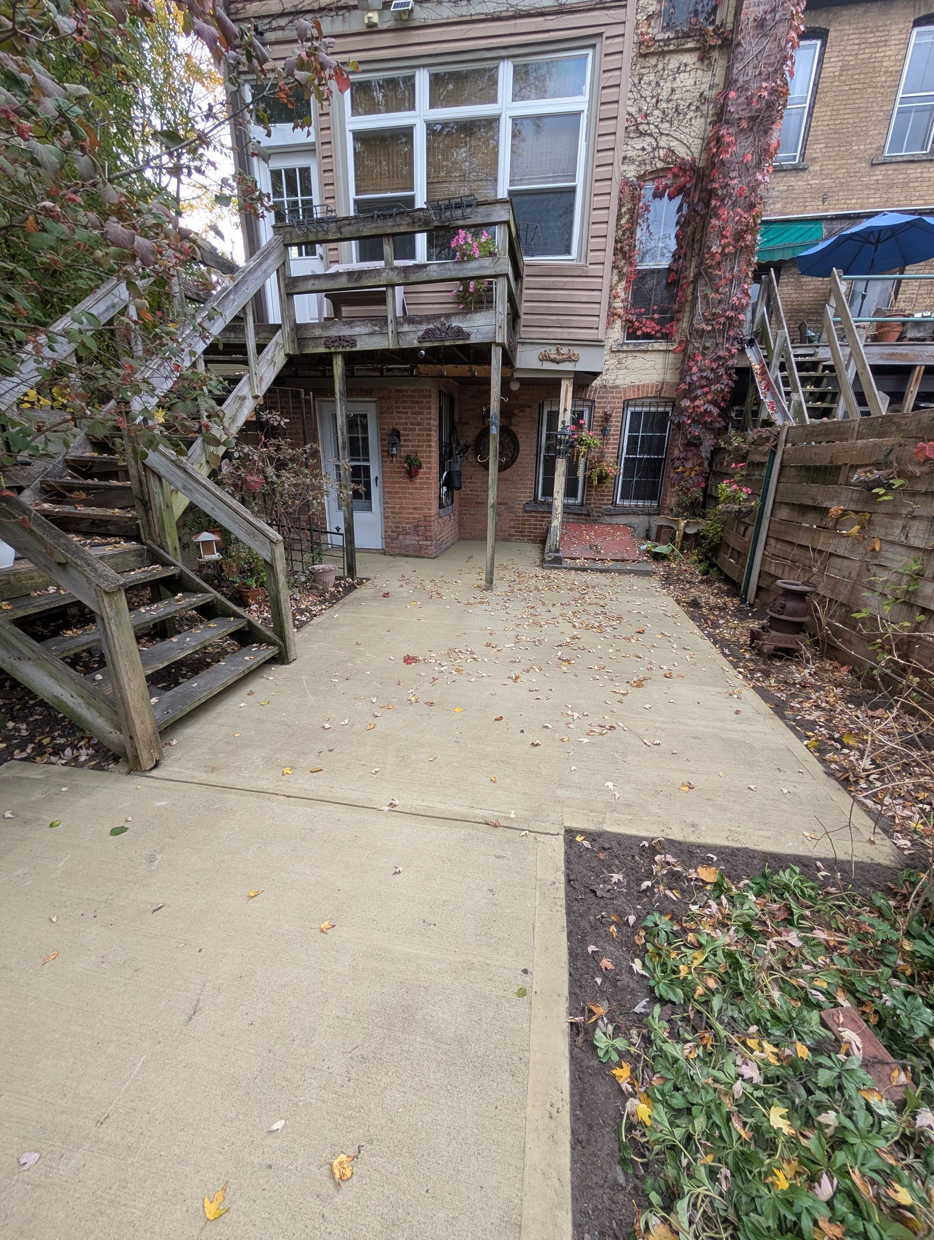 A concrete walkway leading to a house with stairs leading up to it.