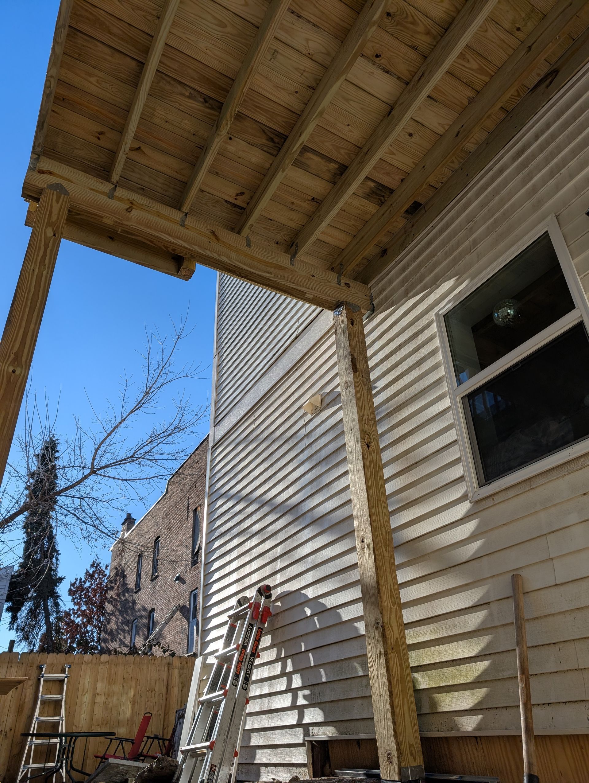 A wooden porch is being built on the side of a house.