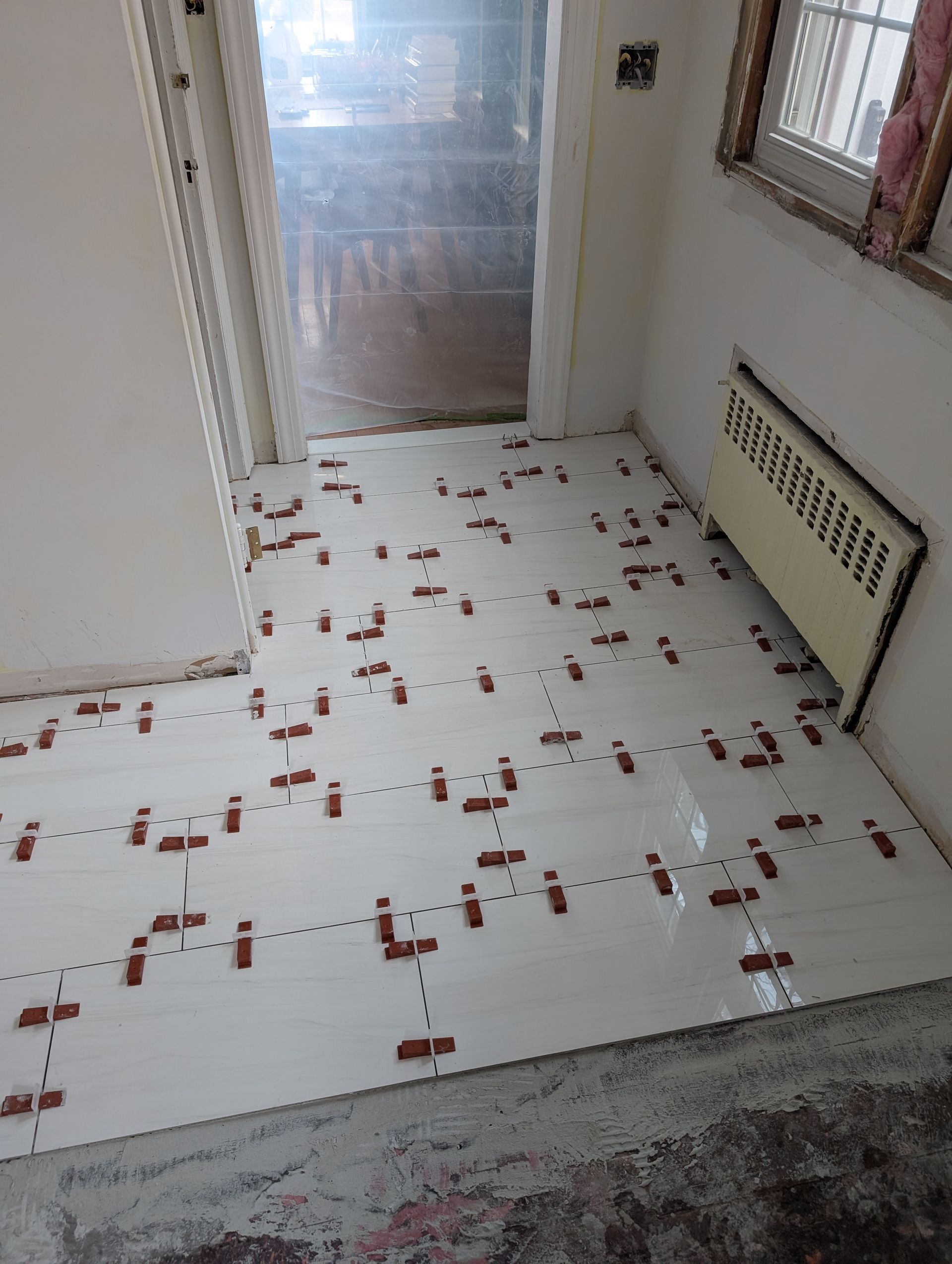 A room with a lot of tiles on the floor and a radiator.