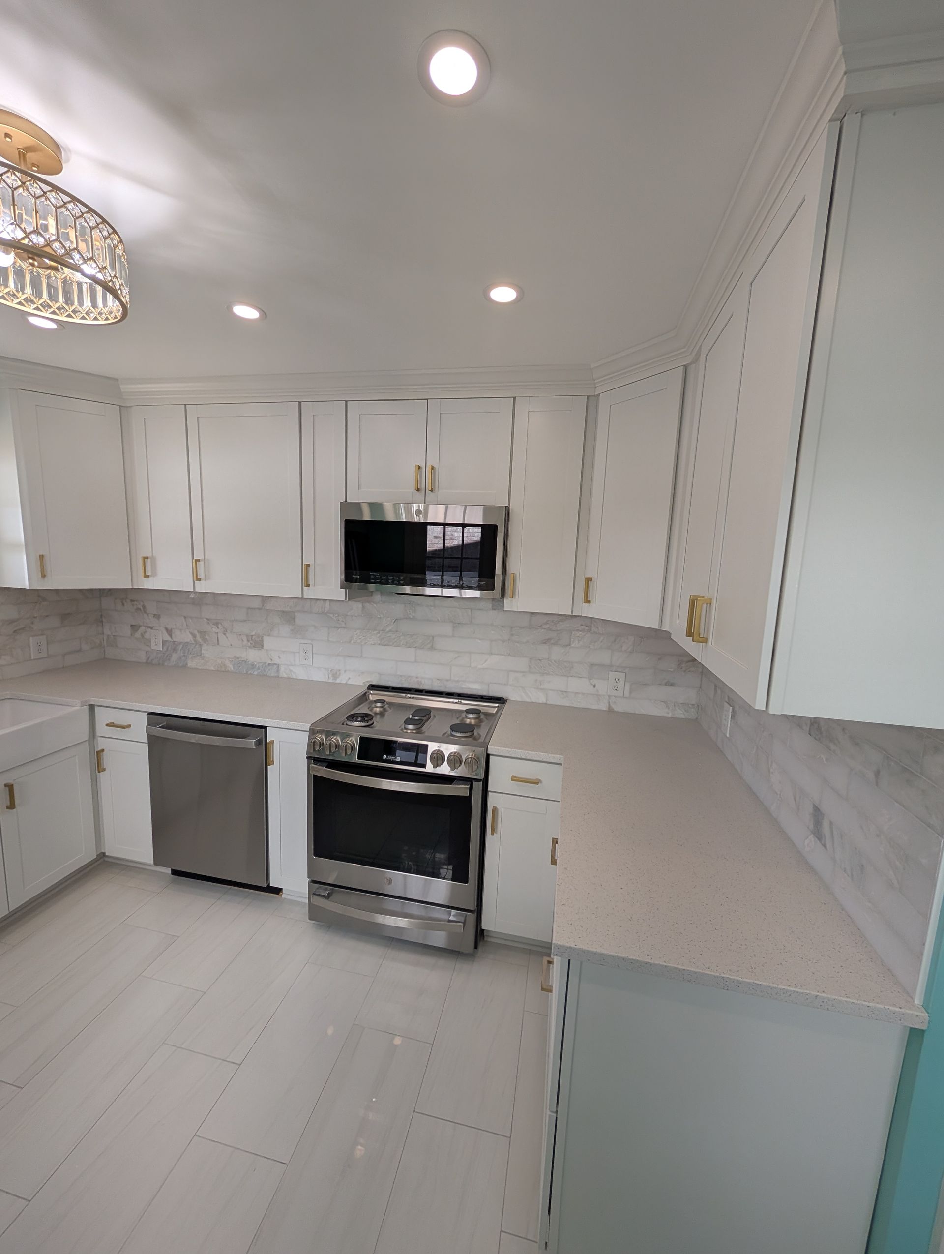 A kitchen with white cabinets , stainless steel appliances , and granite counter tops.