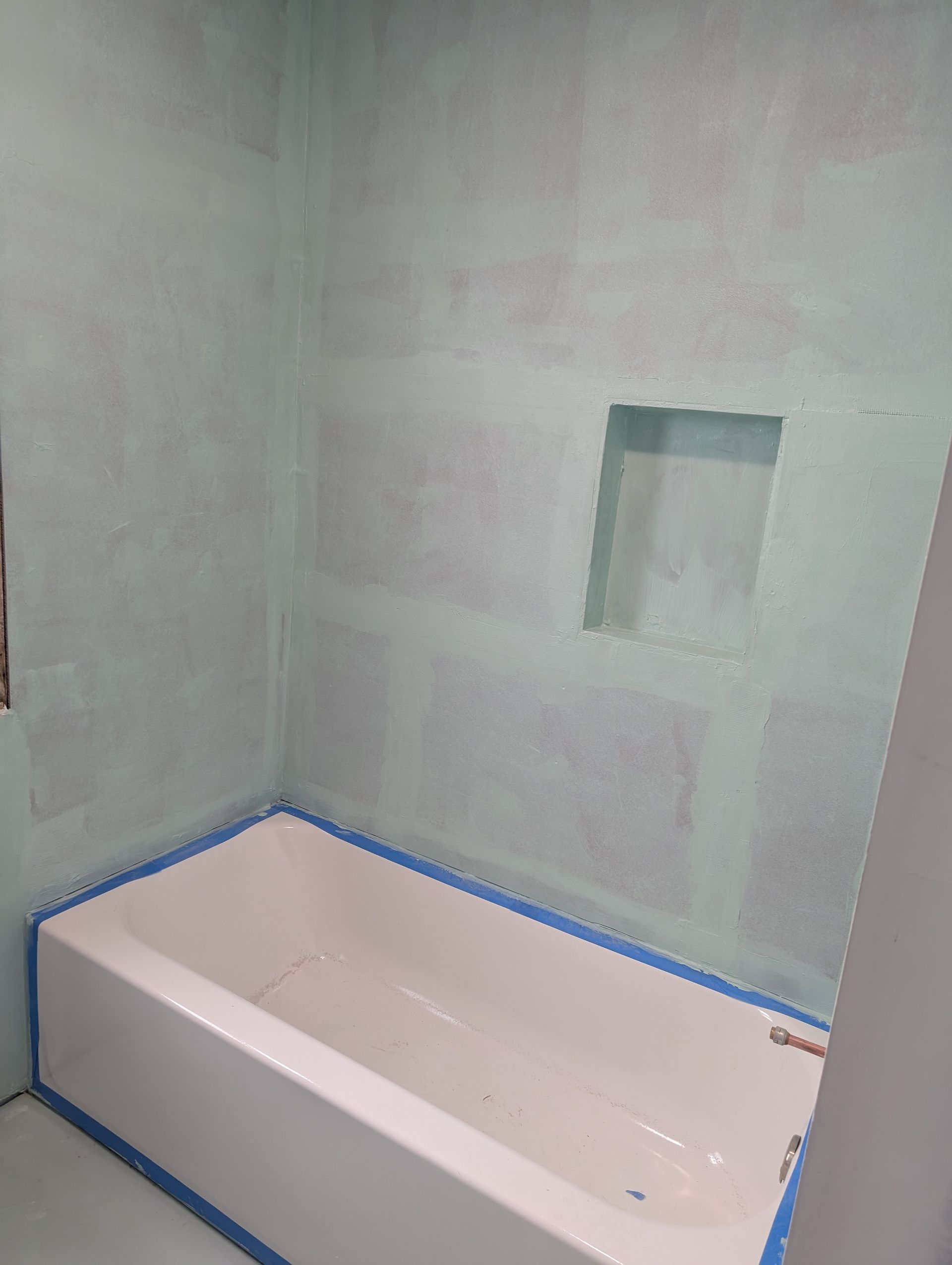 A bathtub is sitting in a bathroom next to a wall.
