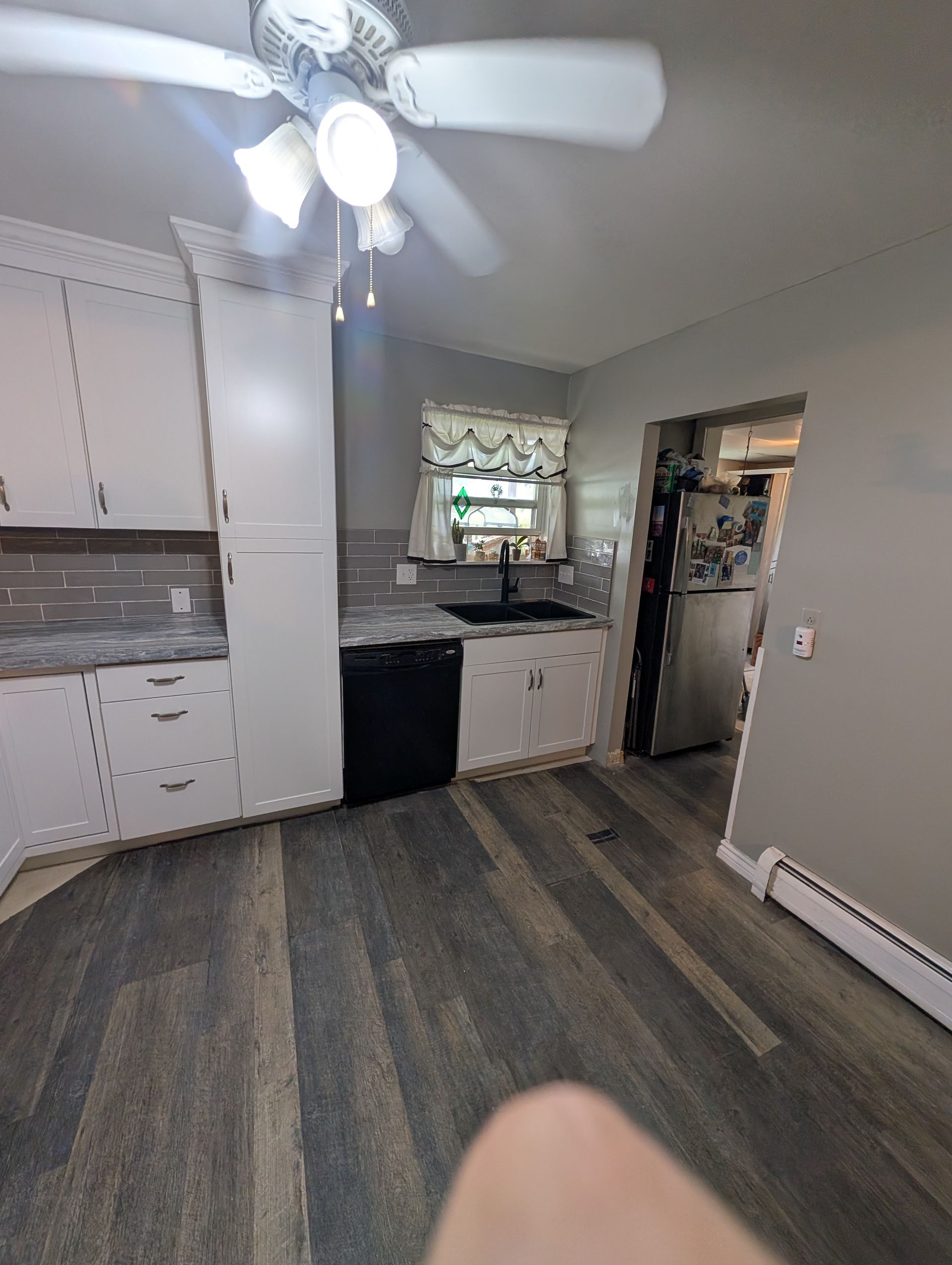 A kitchen with a ceiling fan and a sink.