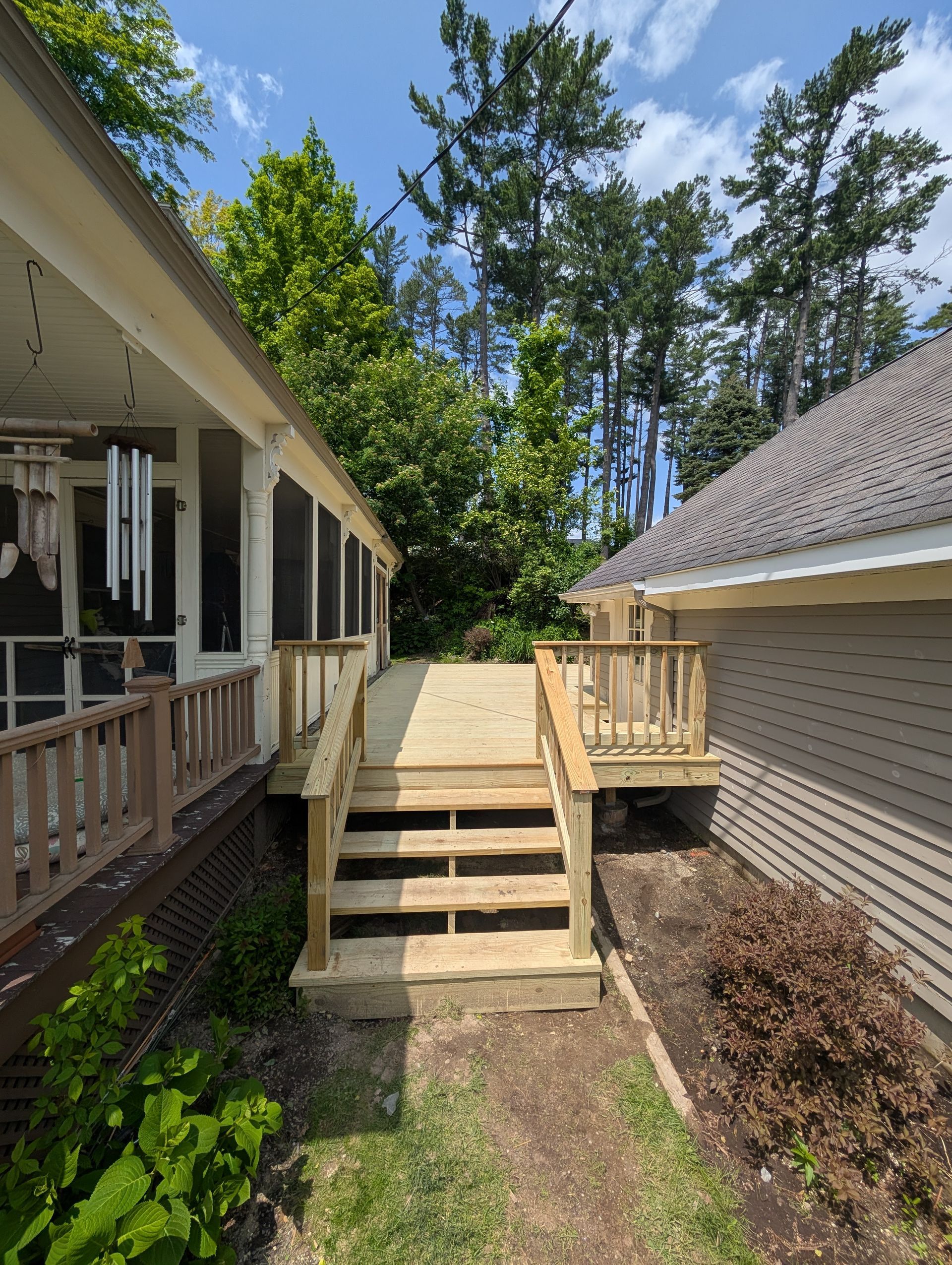 A wooden deck with stairs leading up to it next to a house.