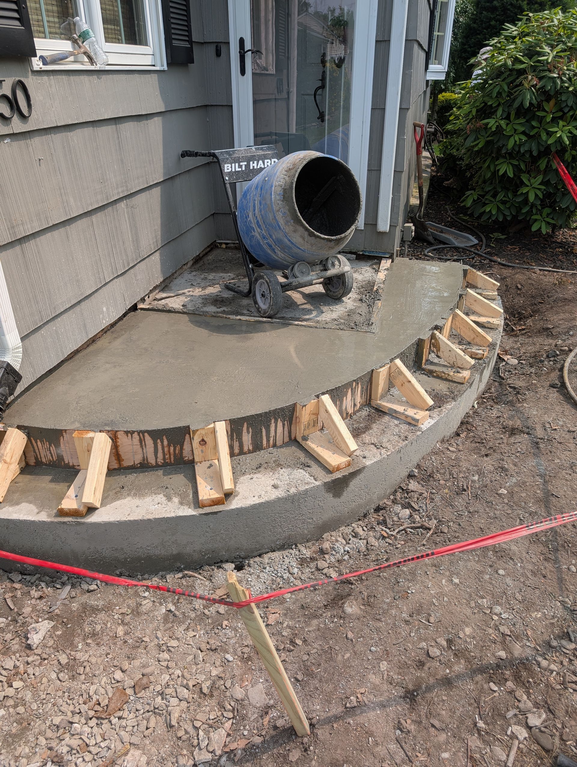 A concrete mixer is being used to mix concrete on a porch.