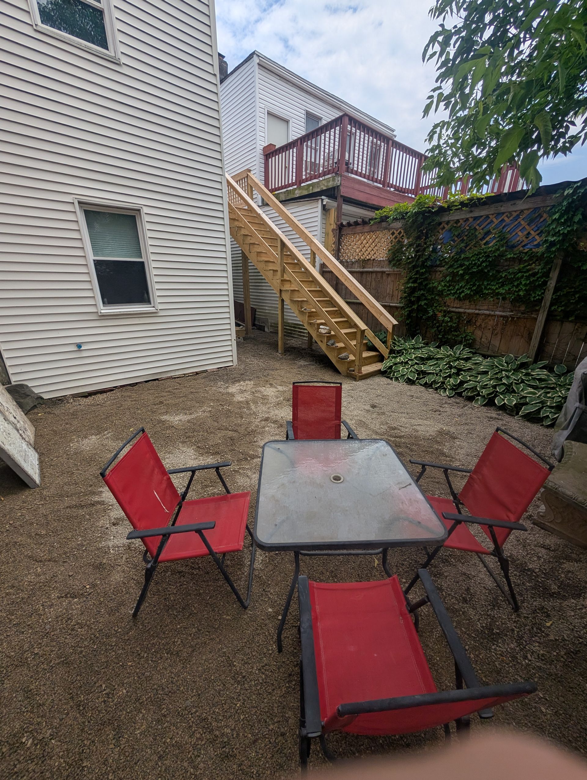 There is a table and chairs in the backyard of a house.