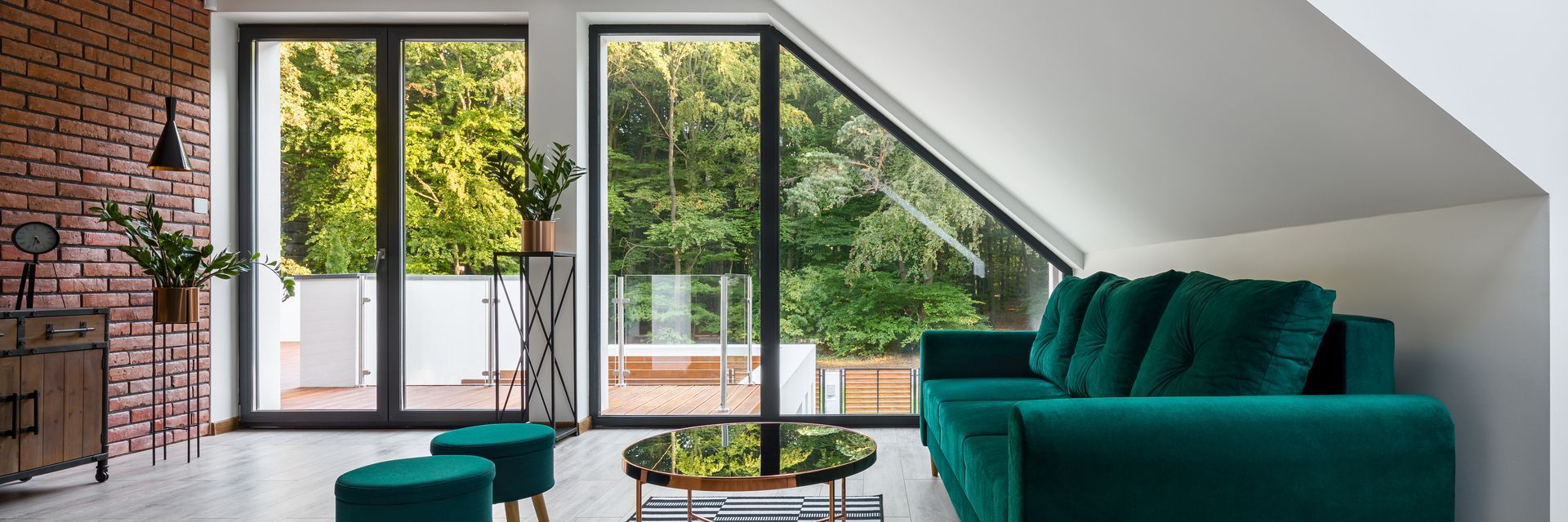 Intérieur d'un salon moderne avec un canapé, des poufs et une table basse en verre devant de grandes fenêtres .