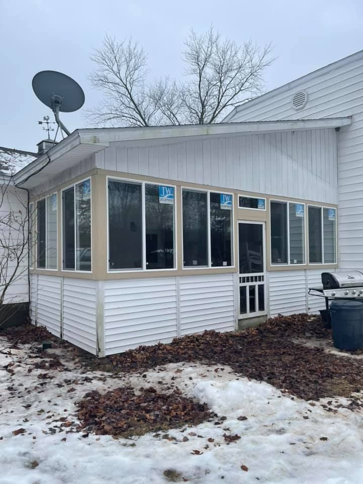 Snowy backyard addition with white siding, many windows, and a satellite dish on the roof