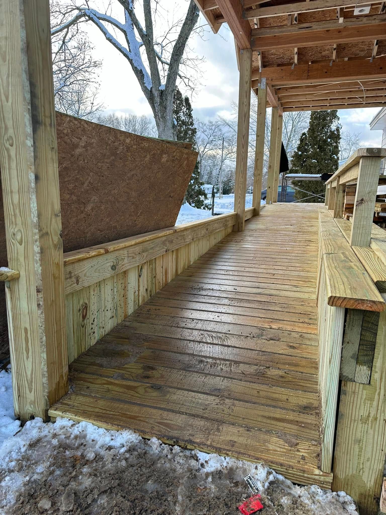 Snow-dusted wooden porch with railings and a view of trees and water beyond