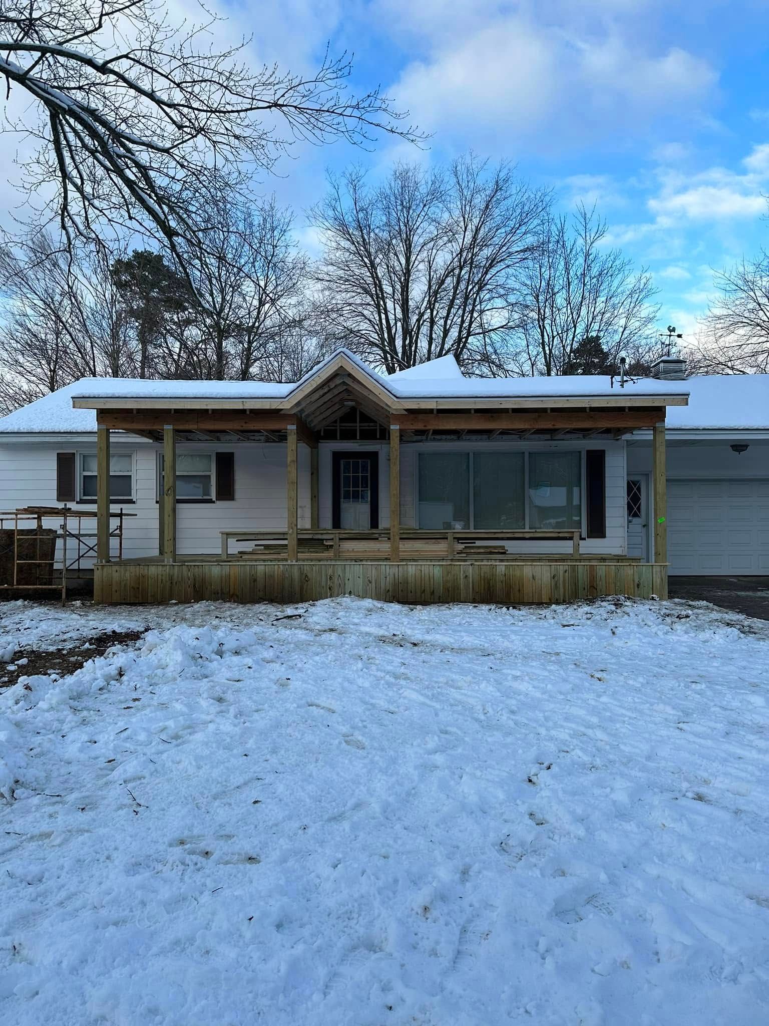Snow-covered single-story house with a small front porch under a blue winter sky