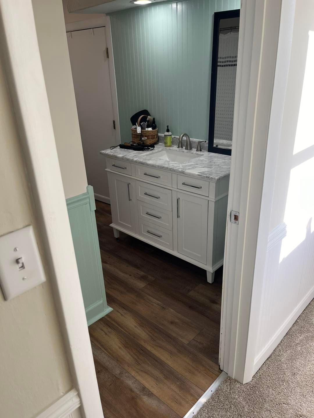 Bathroom vanity with white cabinet and gray countertop in a doorway, wood-look floor and striped wall paneling