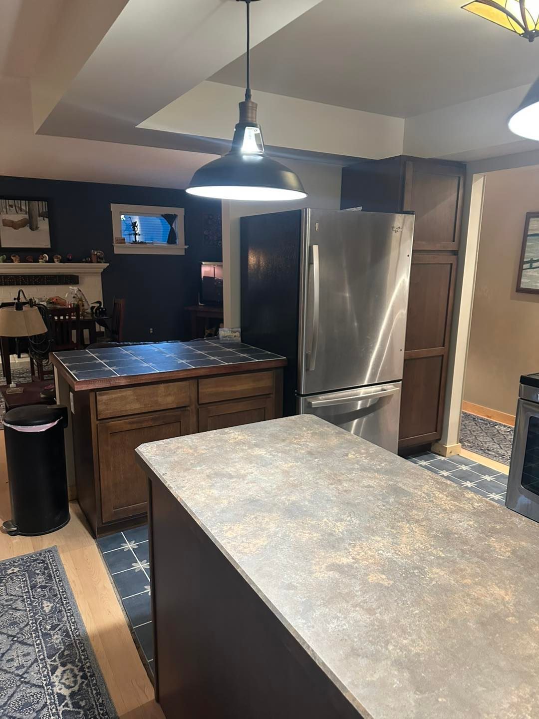 Kitchen with stainless steel fridge, island counter, wooden cabinets, and pendant lighting.