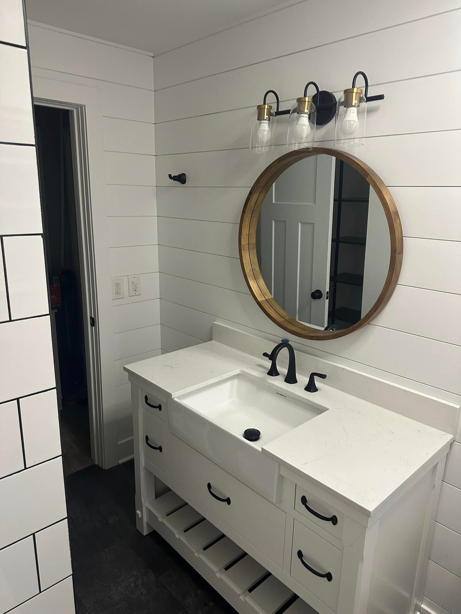 Modern white bathroom vanity with round mirror and black fixtures