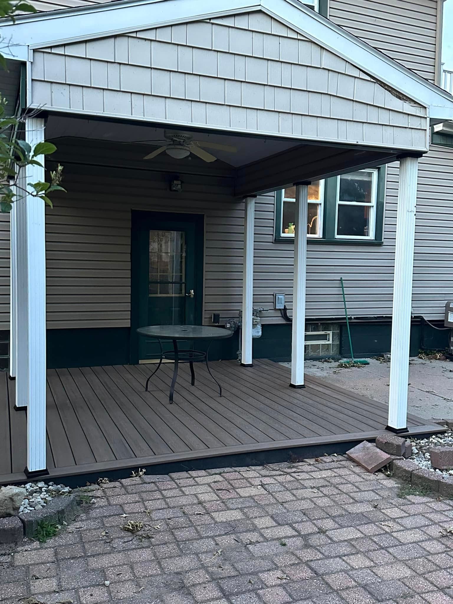 Covered front porch with white posts, gray siding, and a teal door.