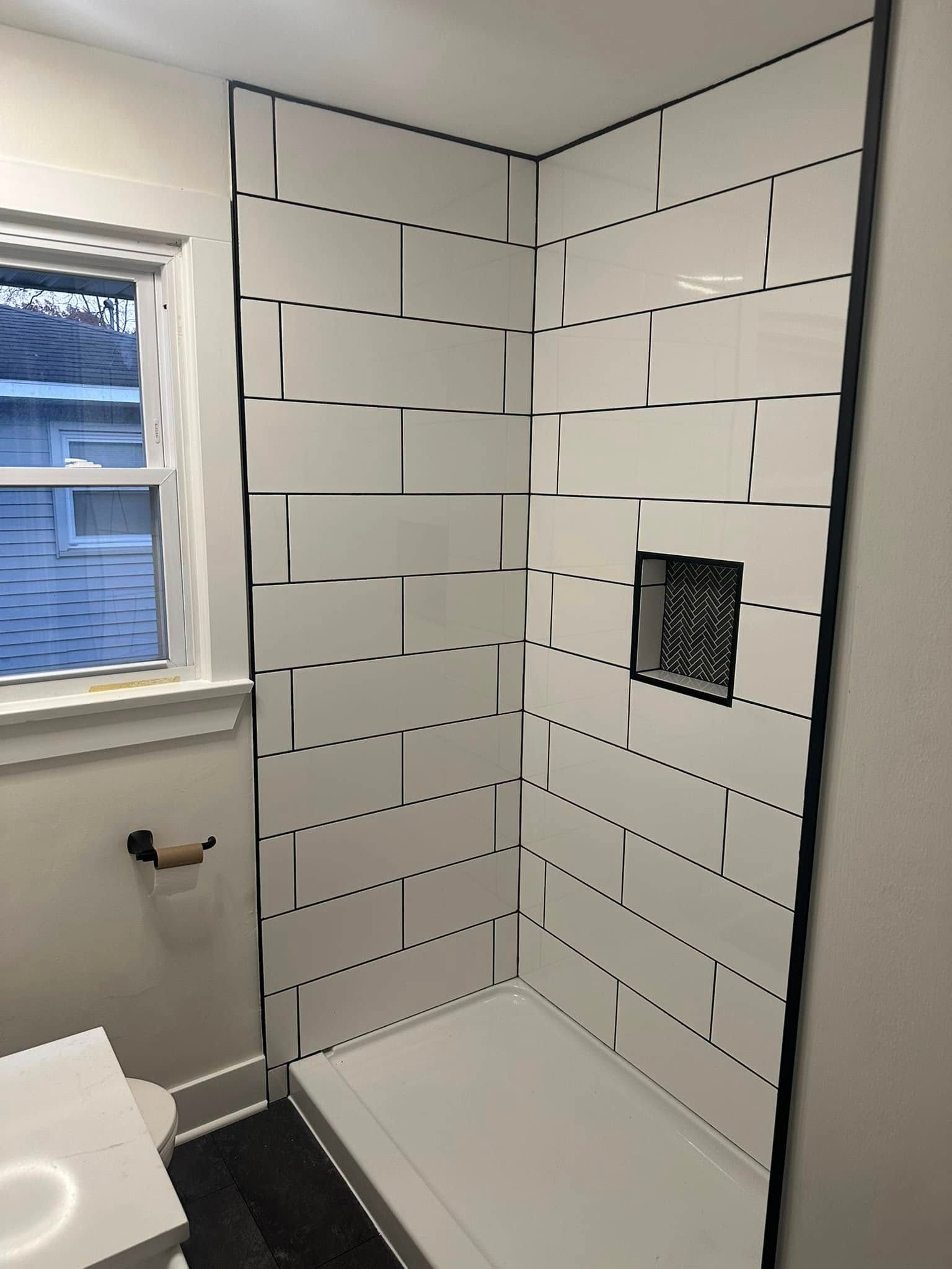 Small bathroom shower alcove under construction with white subway tile and a built-in niche.