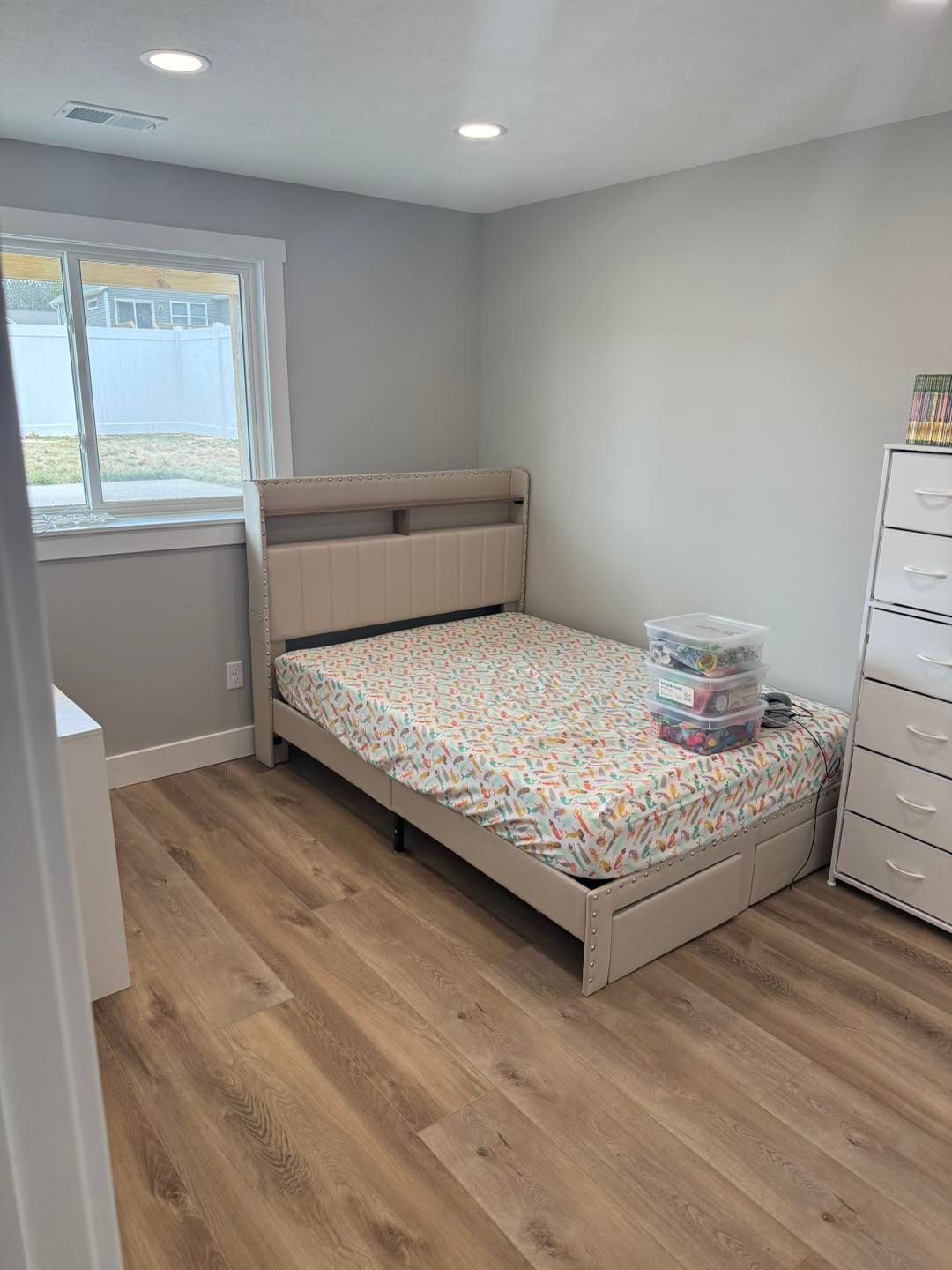 Small bedroom with a bed, dresser, window, and wood flooring