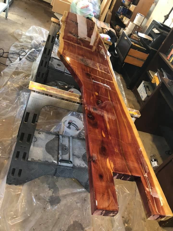 Wooden plank on workbench in a shop, with tools and a clamp nearby.
