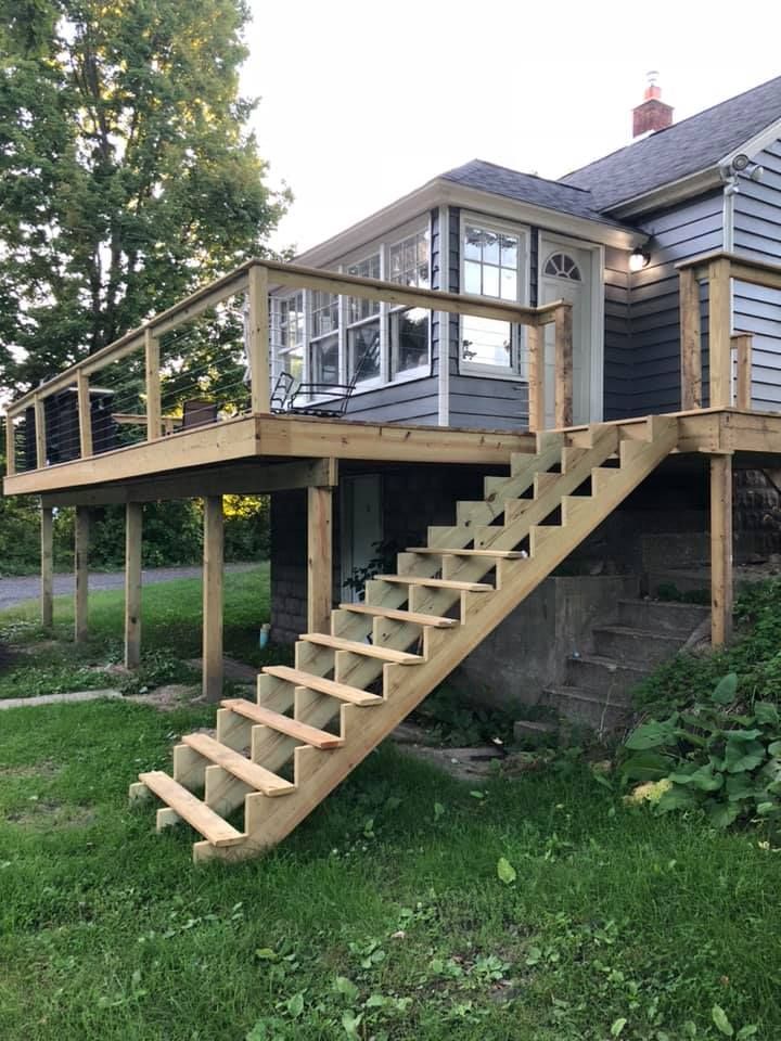 Wooden deck with stairs attached to a house in a grassy yard