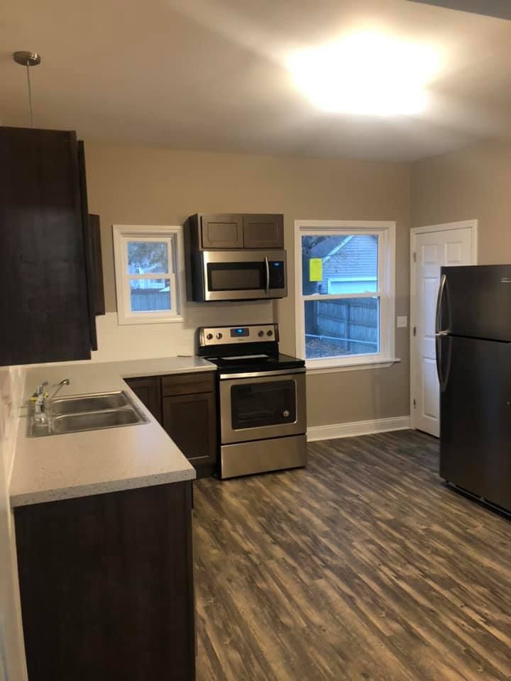 Small modern kitchen with dark cabinets, stainless appliances, and two windows