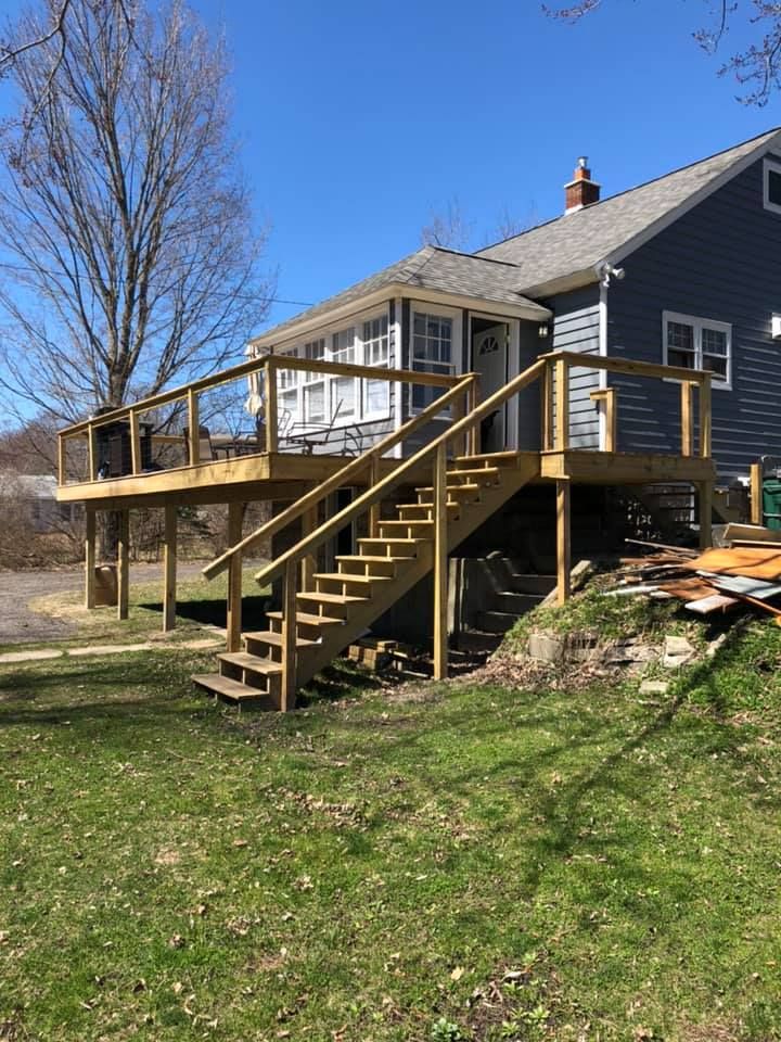 Wooden deck with stairs on a house, viewed from a grassy yard on a sunny day