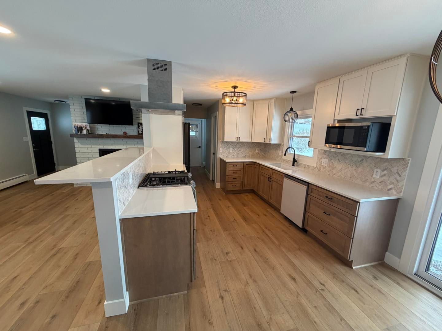 Bright modern kitchen with white cabinets, wood floors, island, and stainless-steel appliances