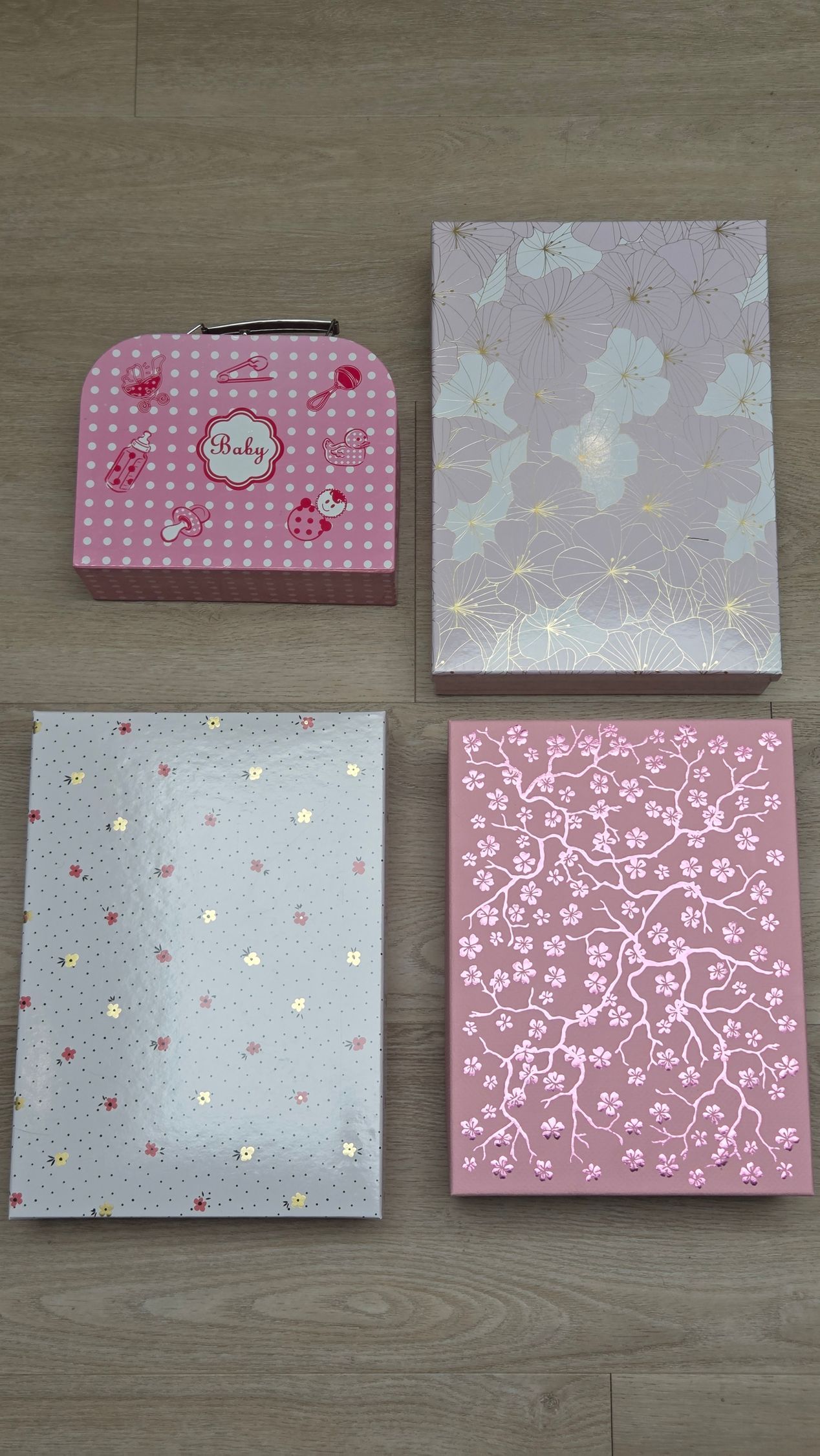 Vier notitieboekjes met pastelkleuren en een roze mini-etui liggen uitgestald op een houten vloer.