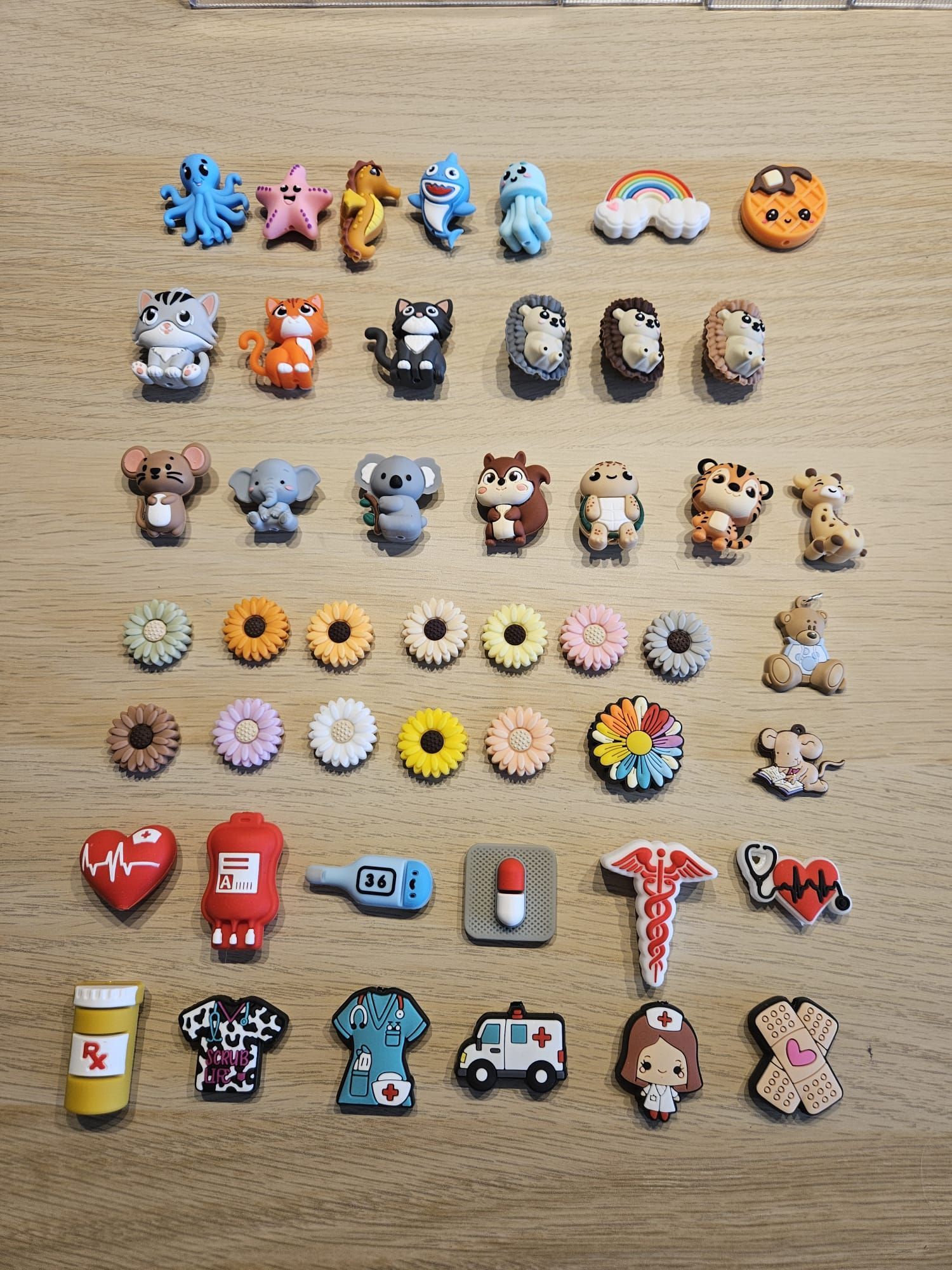 Een assortiment kleine, kleurrijke speelgoedbedeltjes en beeldjes, in rijen uitgestald op een houten ondergrond.